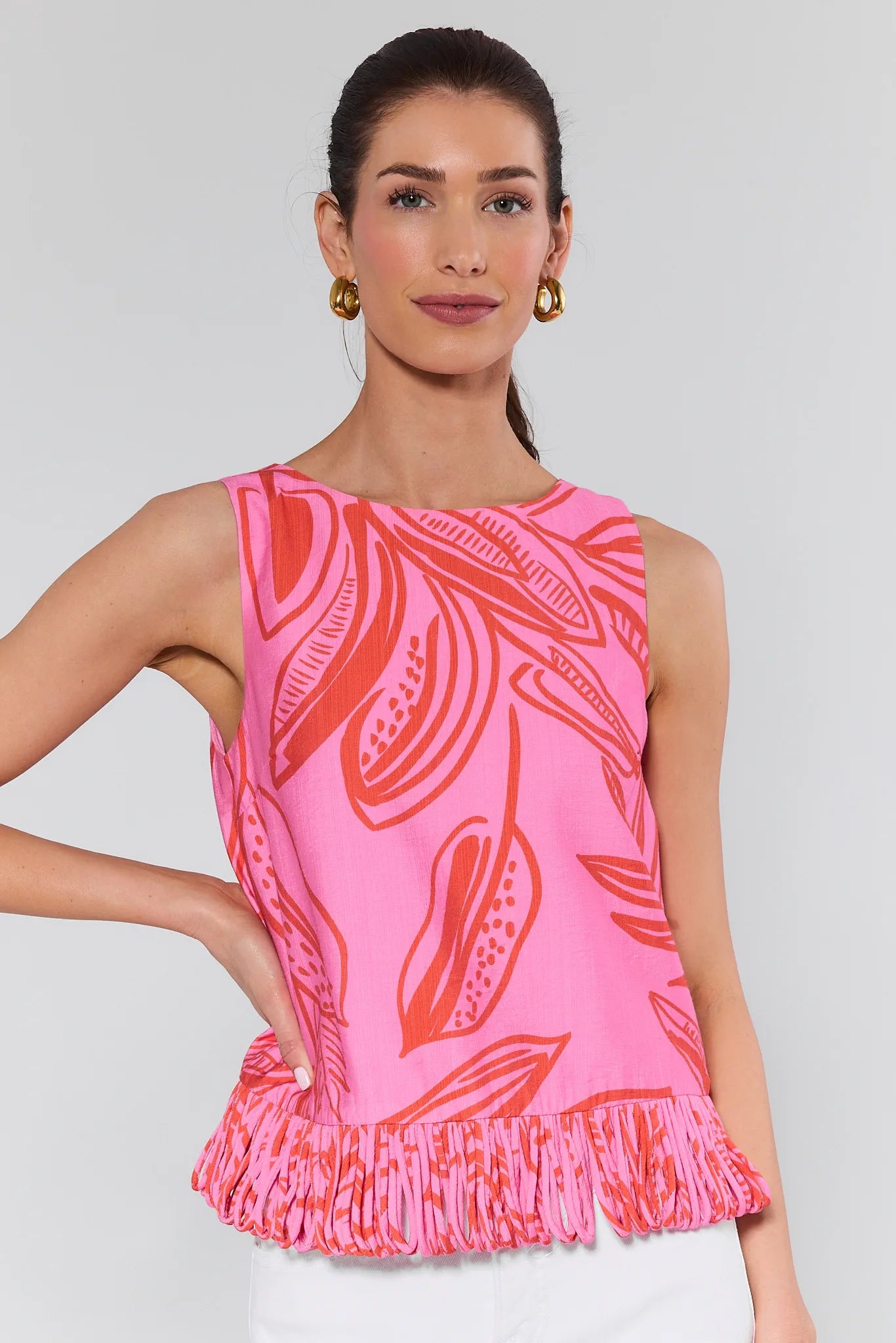 Woman wearing a pink sleeveless top with red leaf pattern on a plain background