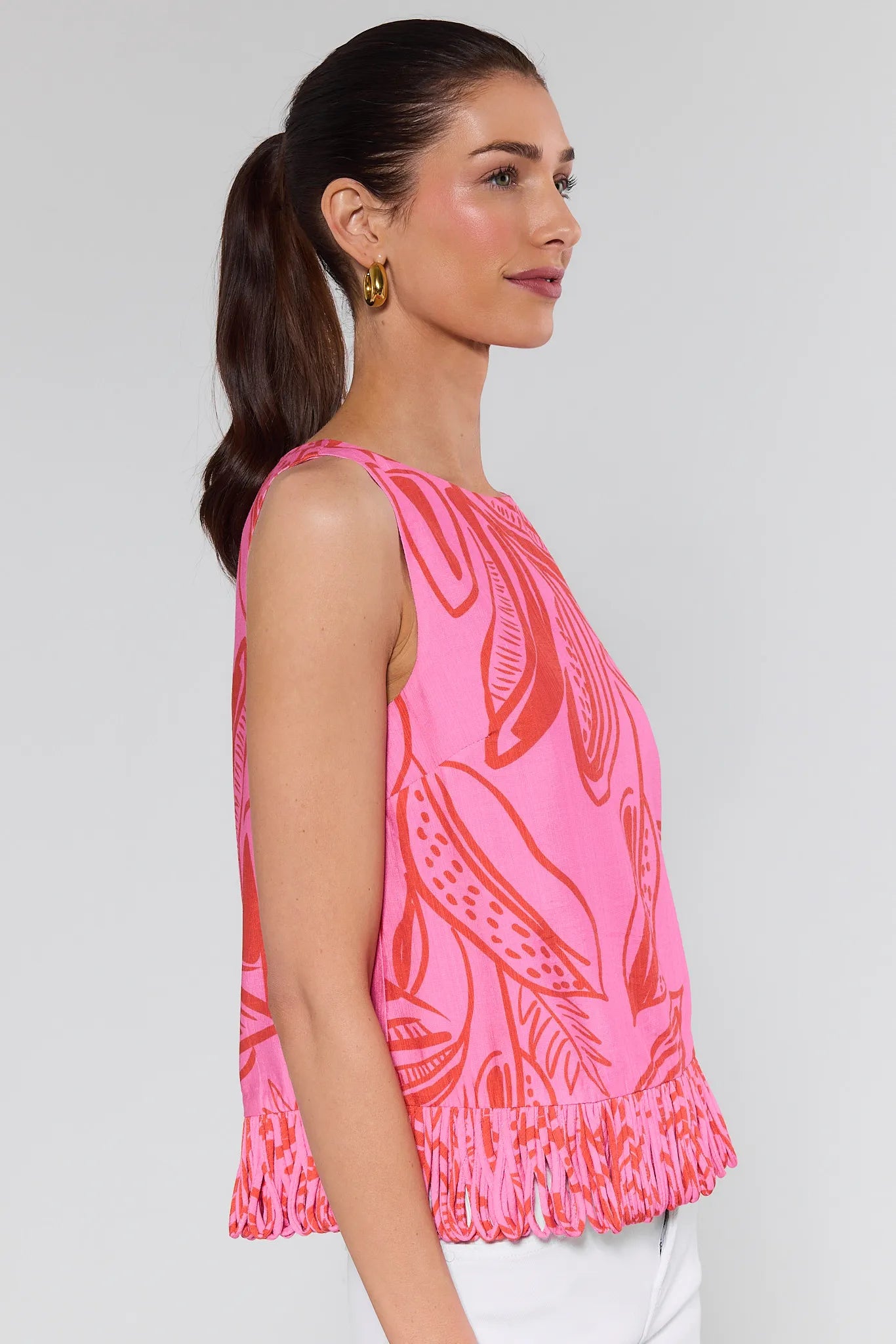 Woman wearing a pink sleeveless top with leaf pattern on a background