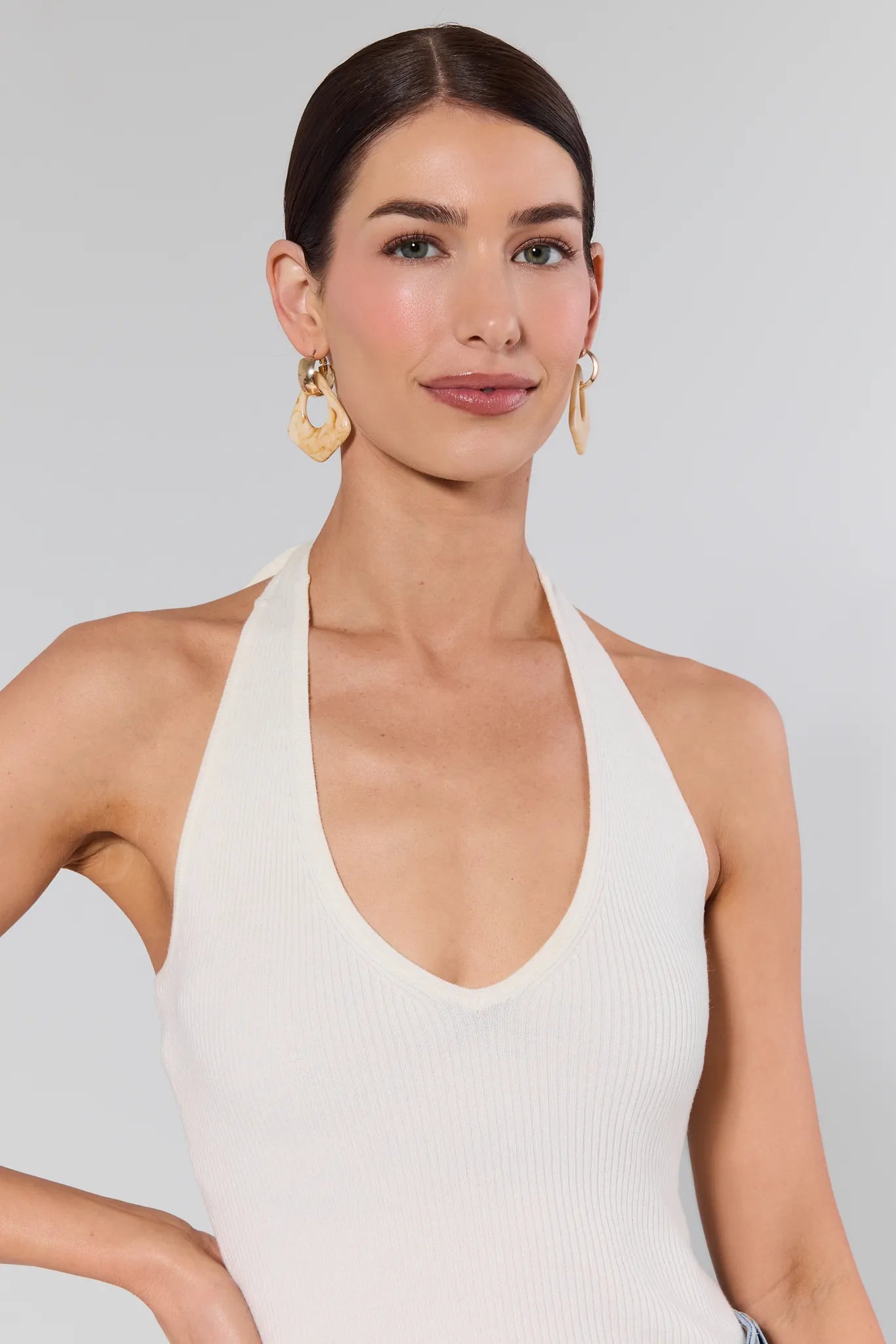 Woman wearing a white halter top against a plain background