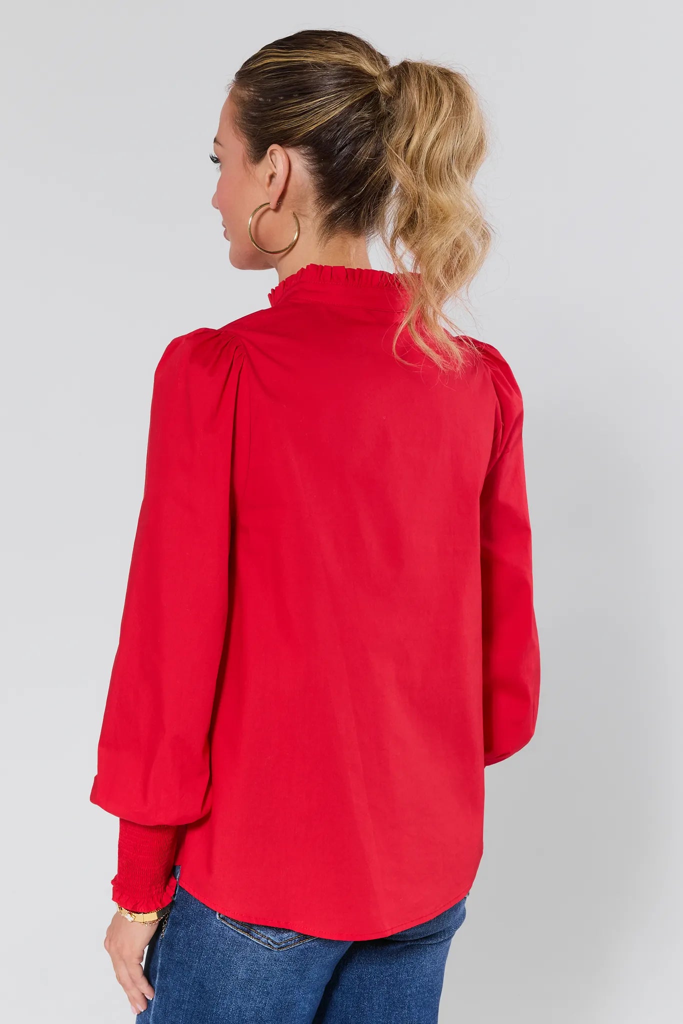 Woman wearing a Della Red Button Up Top and blue jeans against a plain background