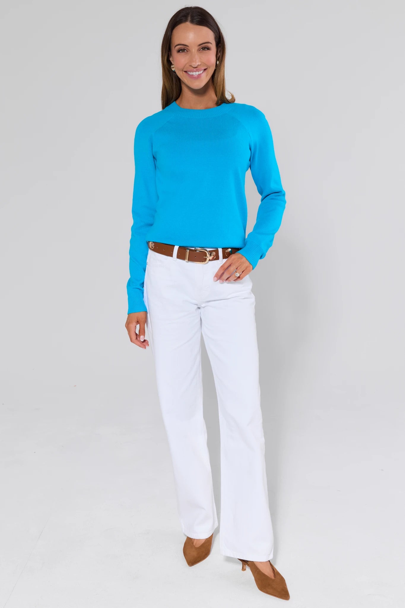 Woman wearing a blue top and white pants on a gray background
