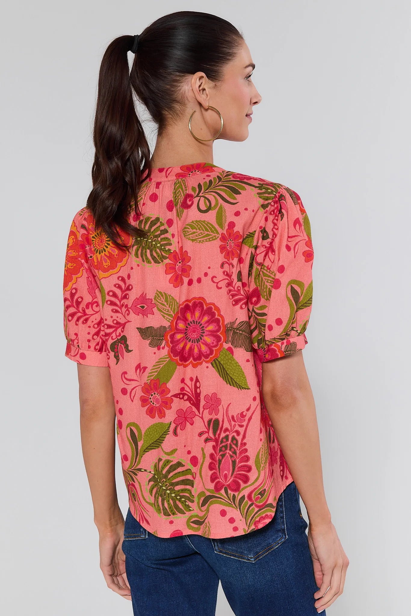 Woman wearing a pink floral blouse with a plain background