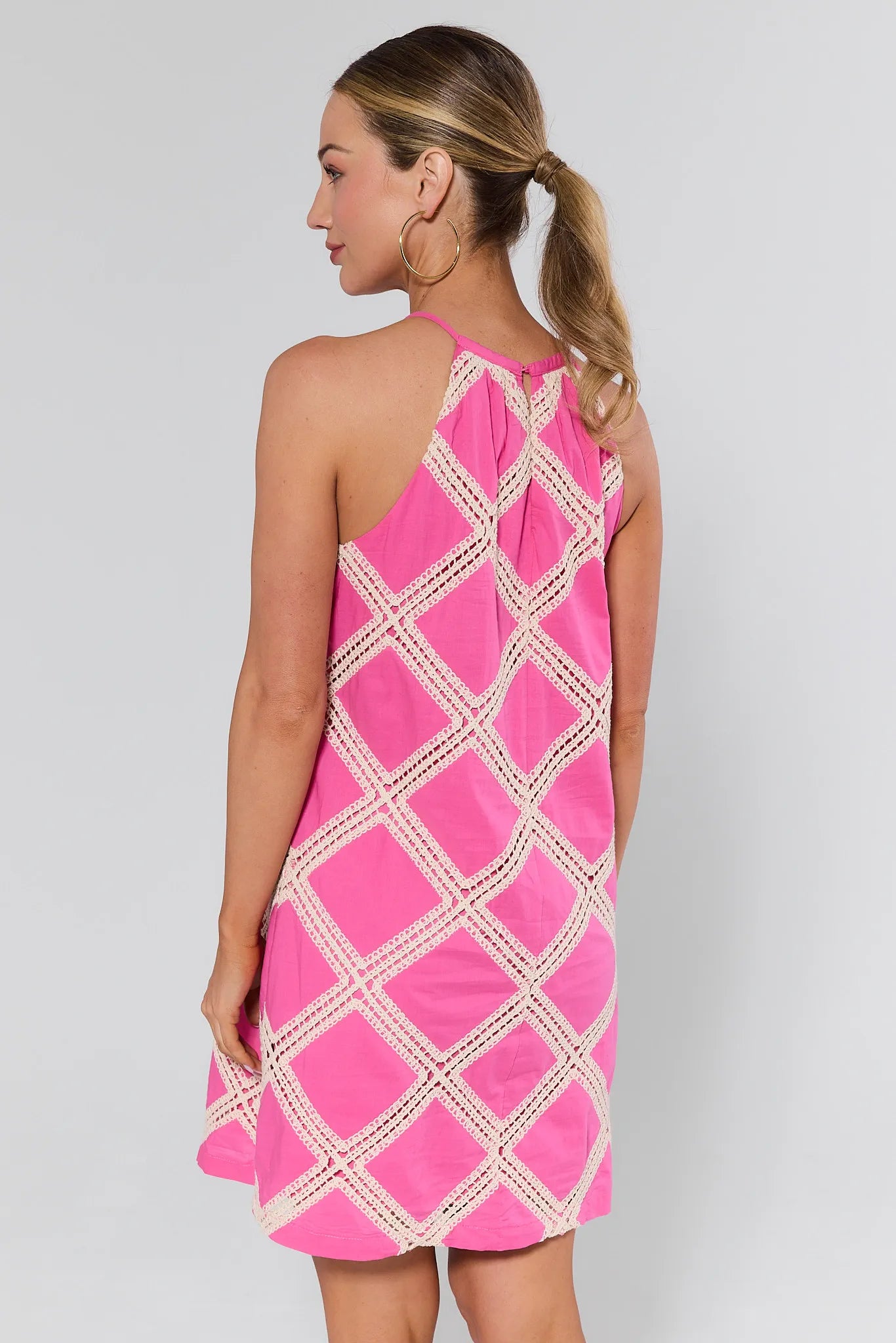 Woman wearing a pink dress with white lace details on a background