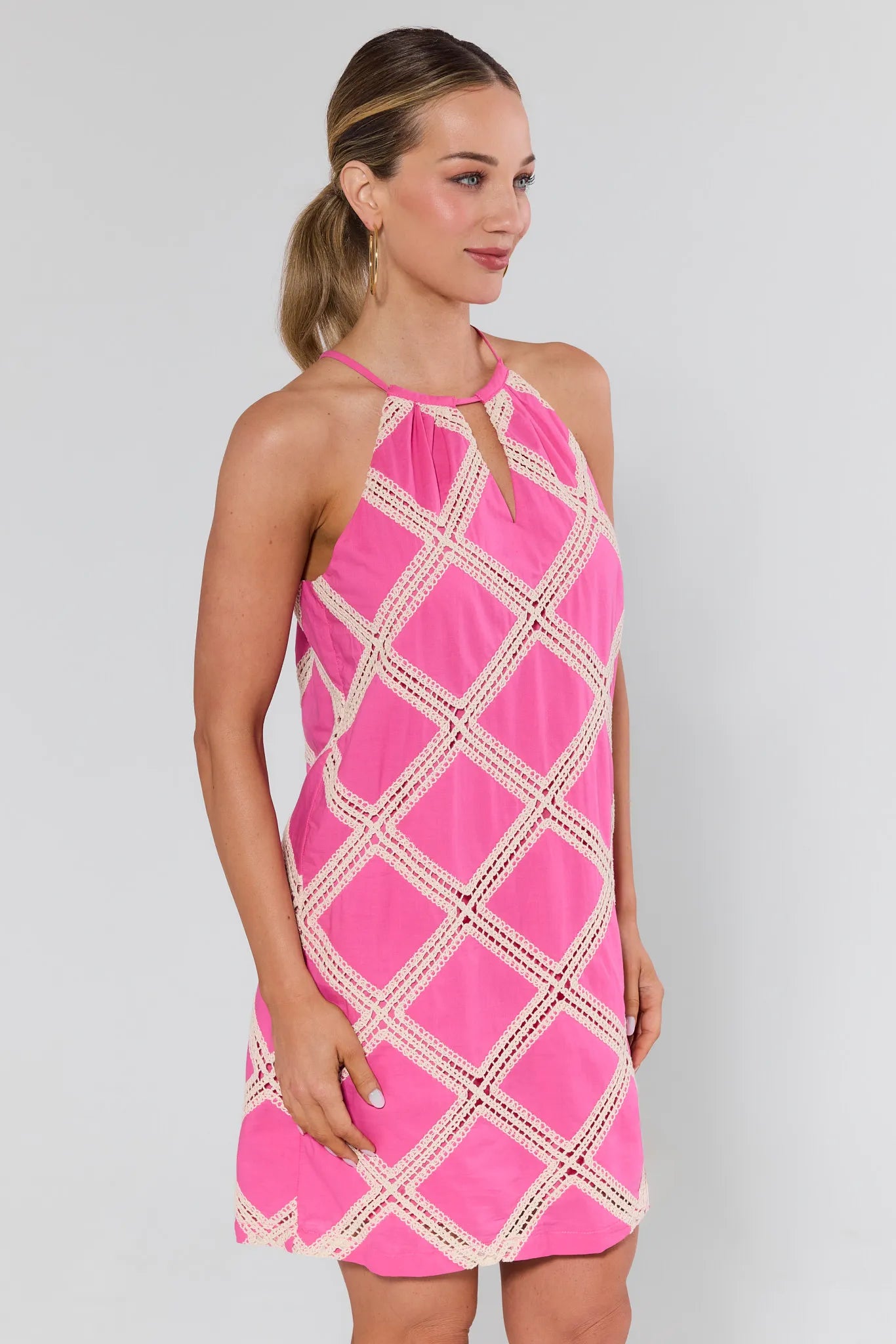 Woman wearing a pink dress with white geometric pattern on a background