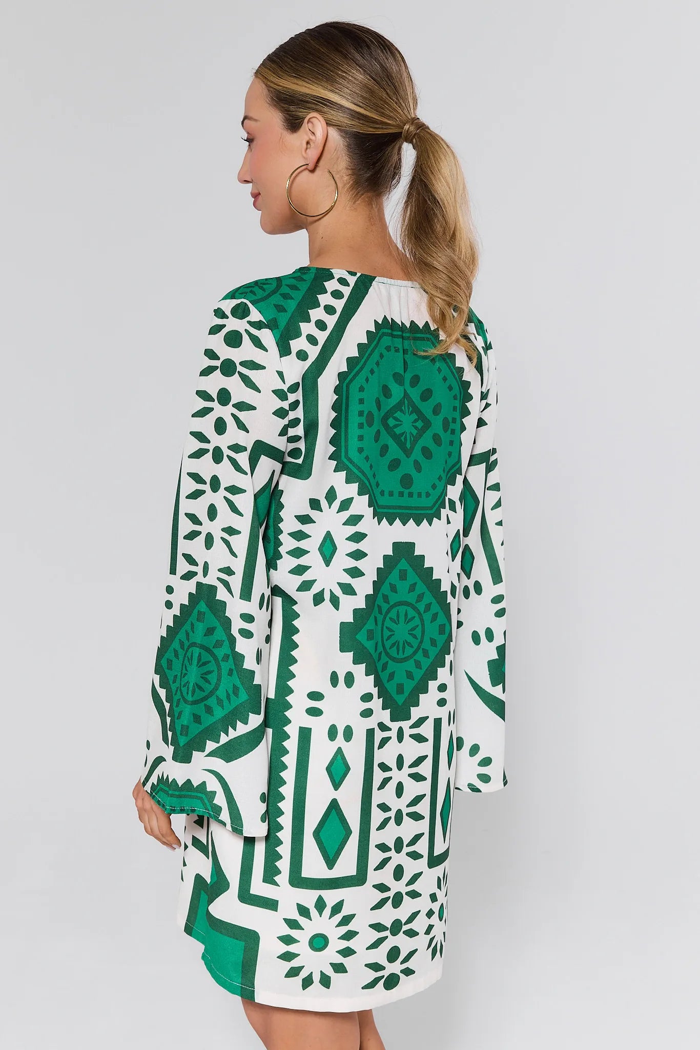 Woman wearing a green and white patterned dress on a plain background