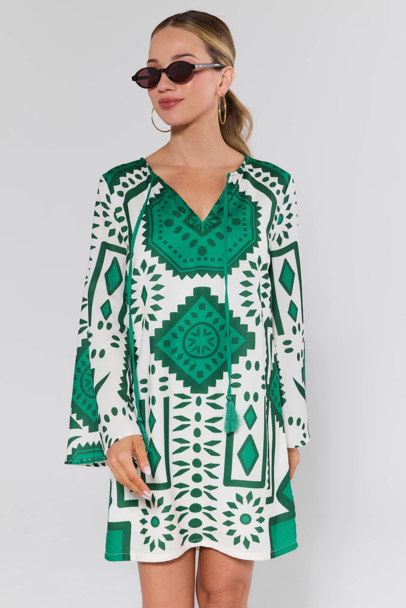 Woman wearing a green and white patterned dress on a gray background