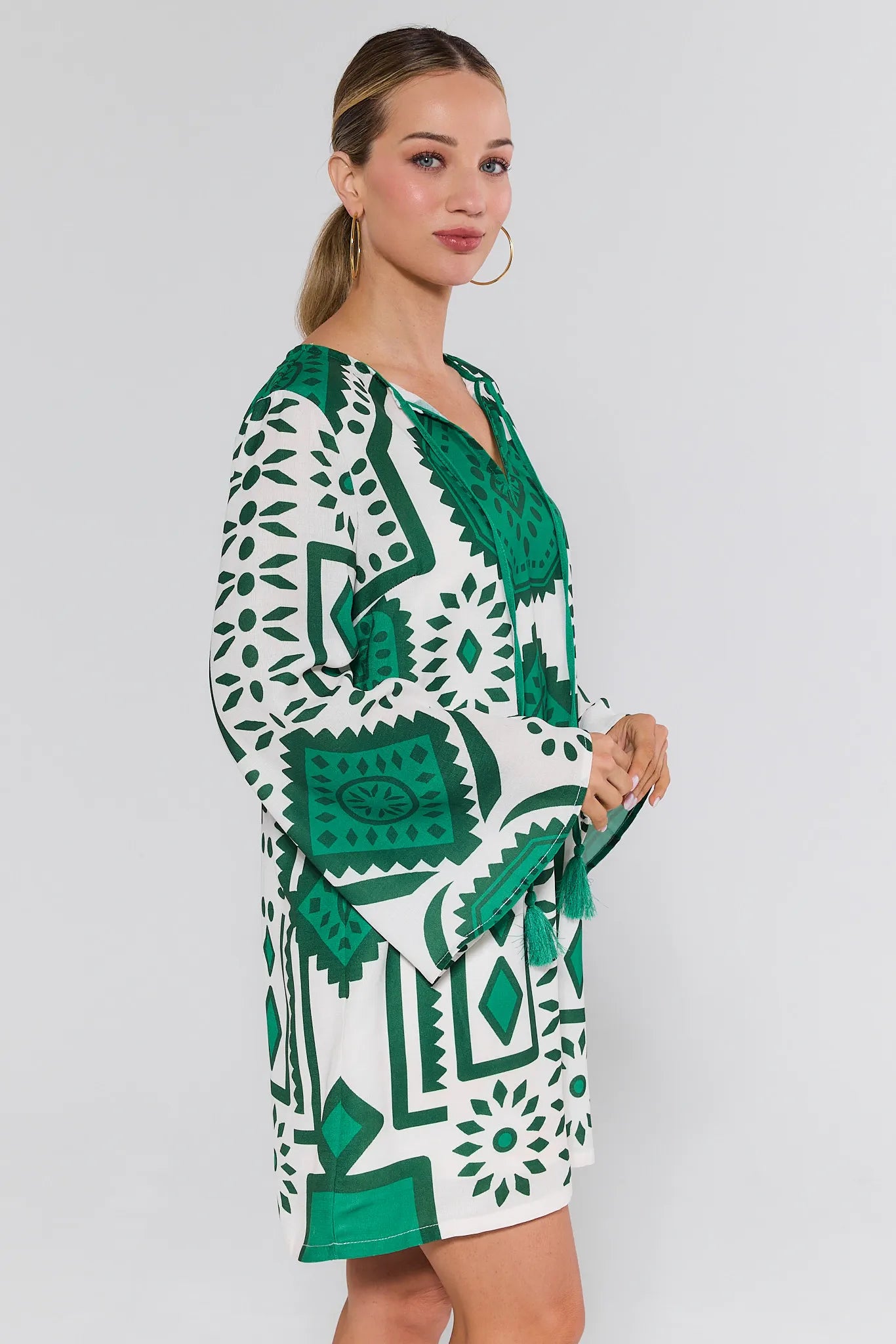 Woman wearing a green and white patterned dress on a plain background