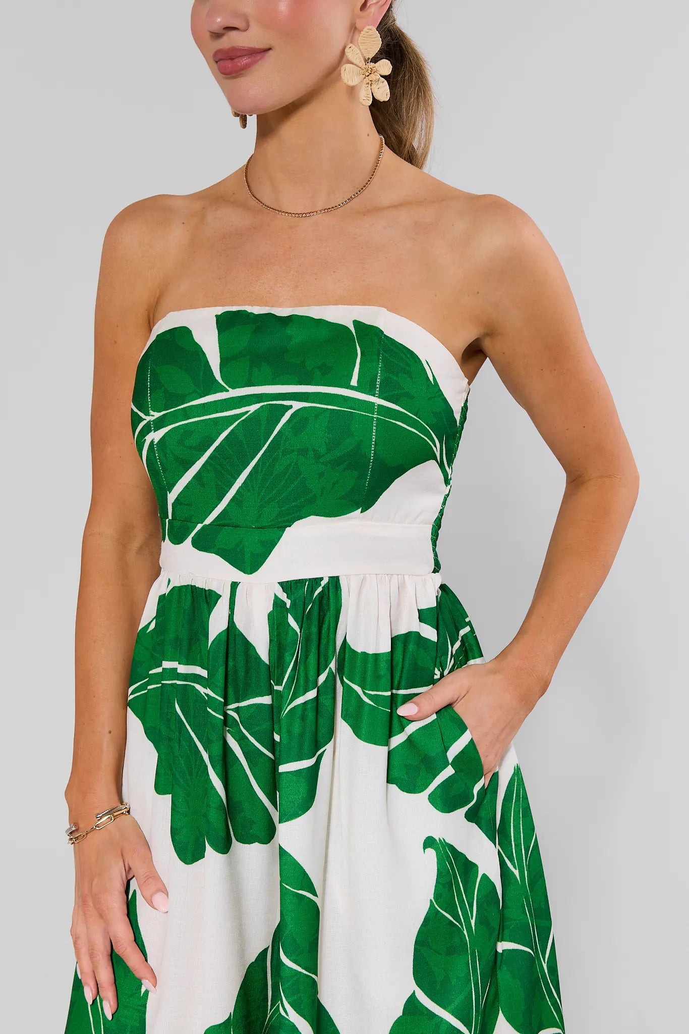 close up Woman wearing a strapless dress with green leaf pattern on a plain background