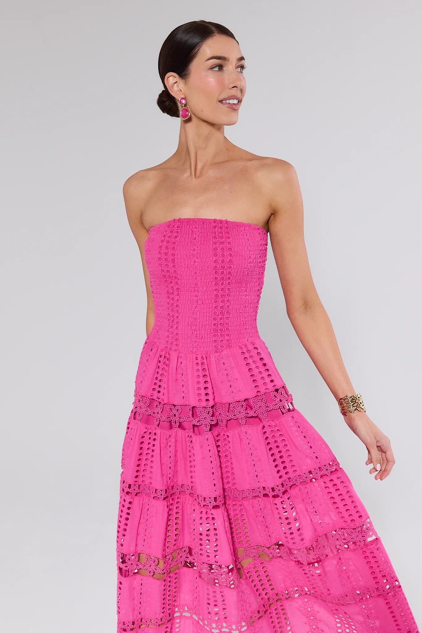 Woman wearing a pink strapless dress with a textured pattern on a light gray background