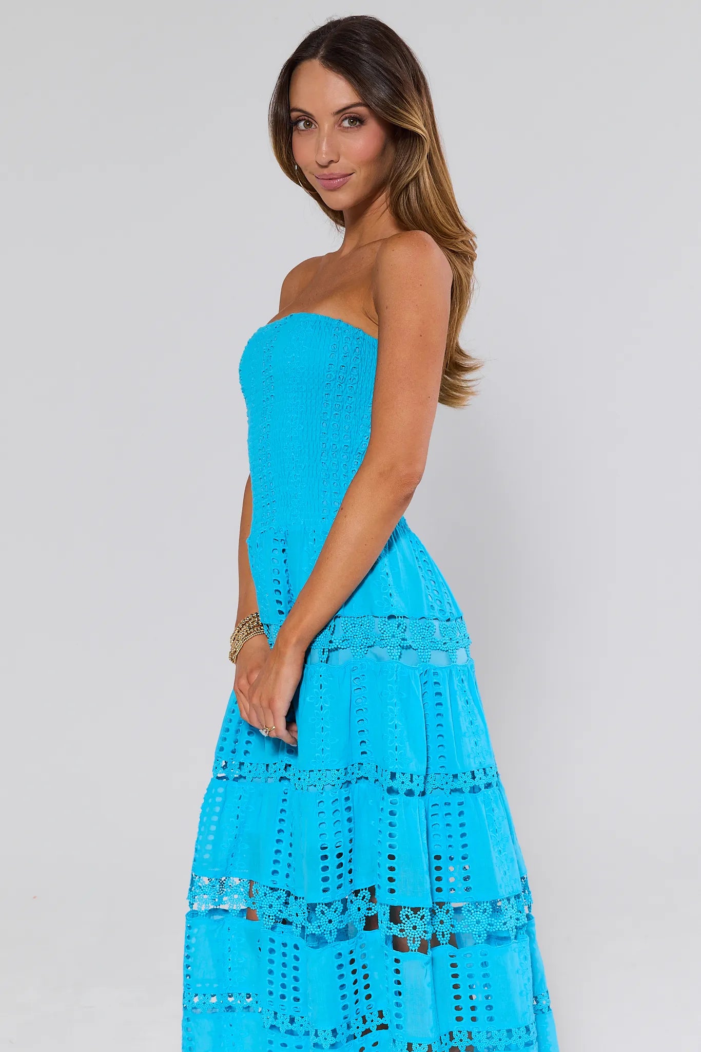 Woman wearing a Cecilia Blue Strapless Midi Dress with lace details on a plain background