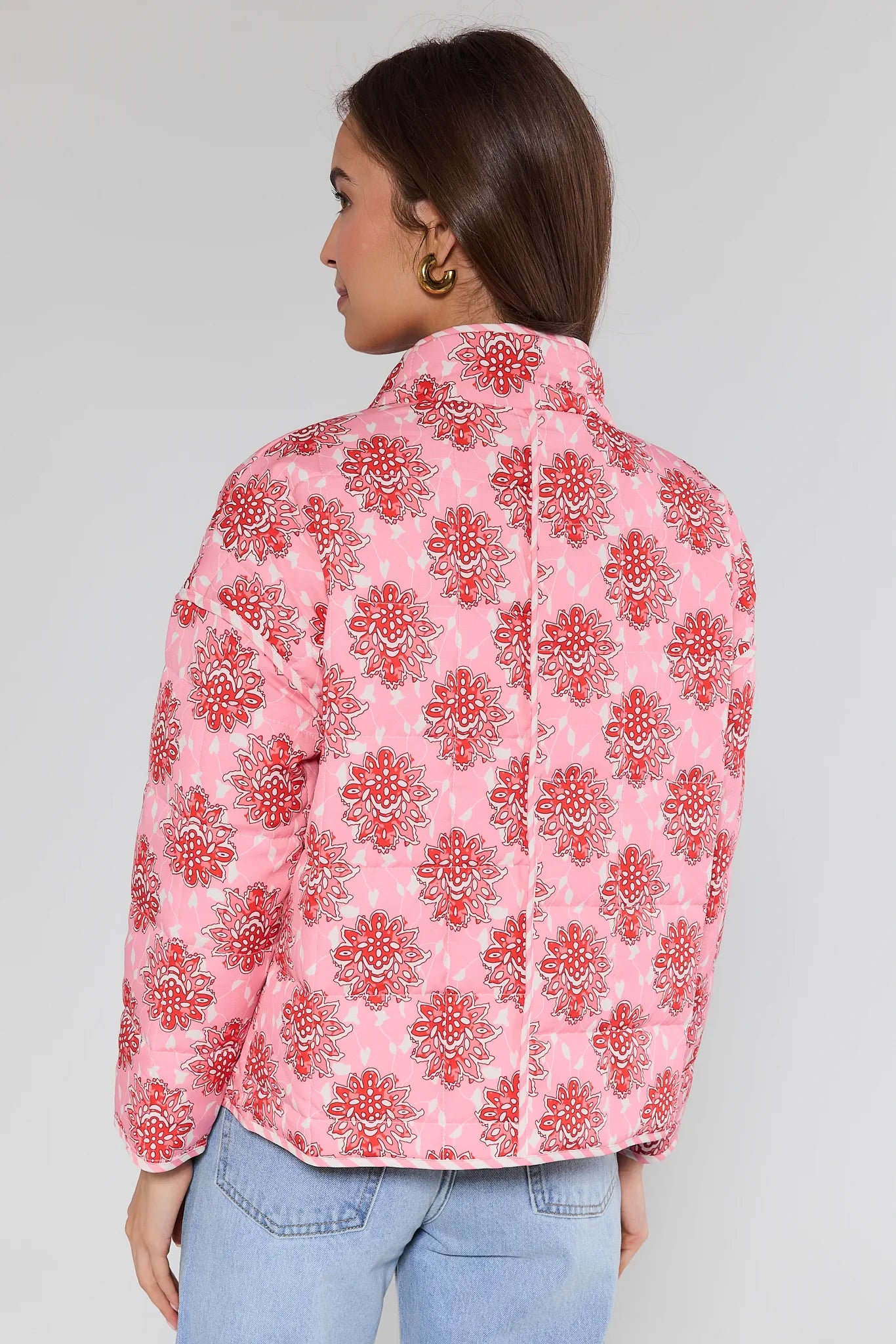 Woman wearing a pink floral patterned shirt against a gray background