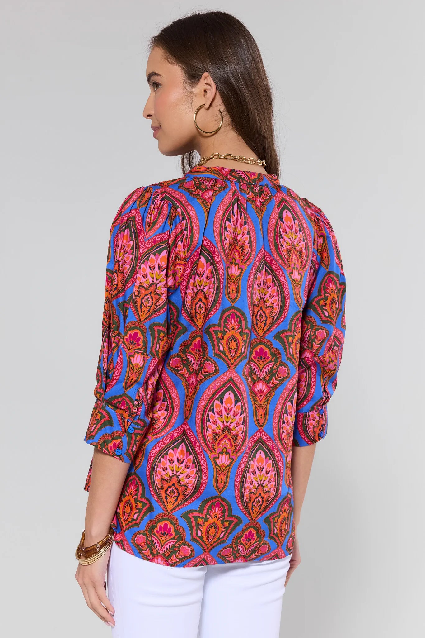 Woman wearing a colorful patterned top on a plain background