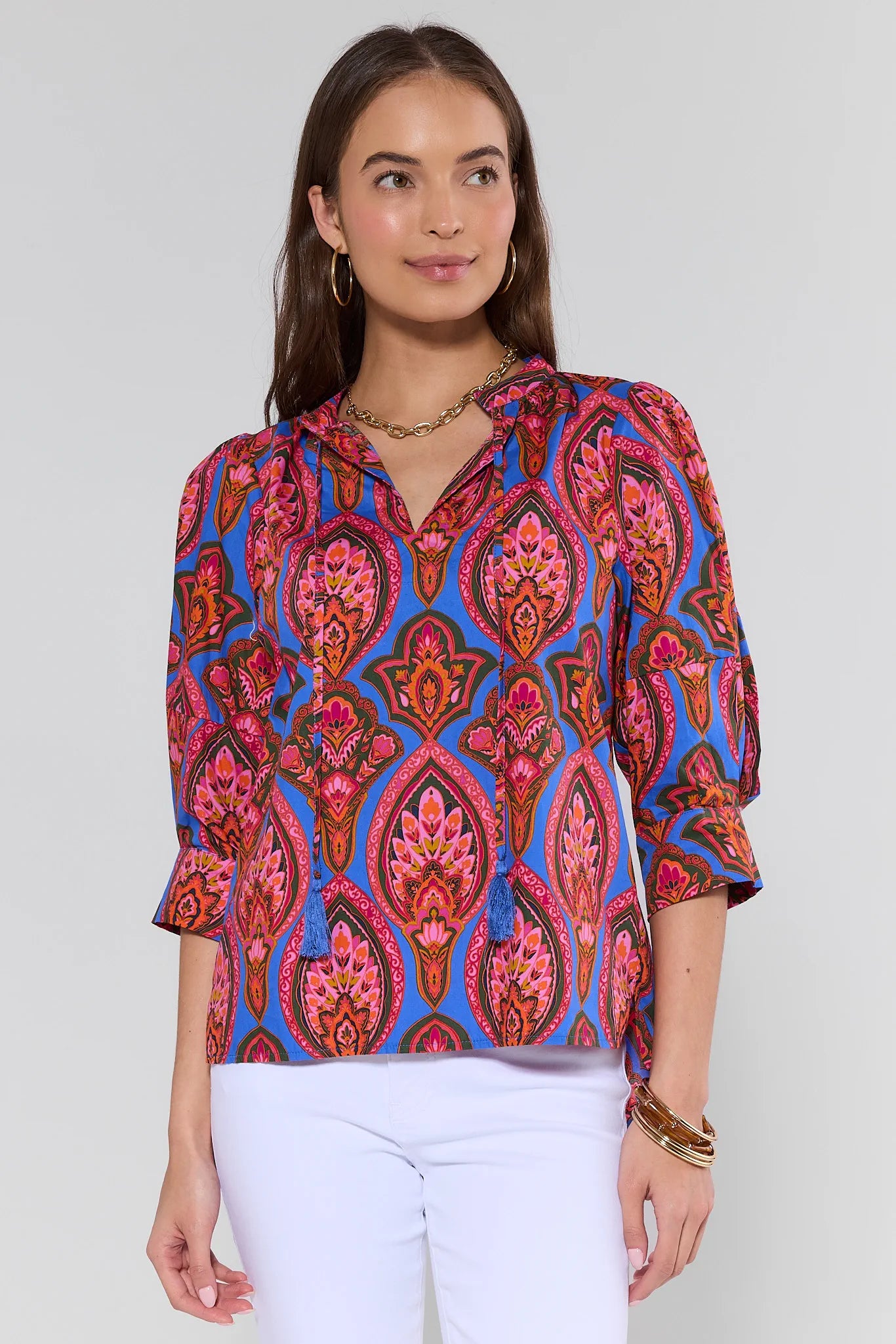Woman wearing a colorful patterned blouse against a plain background