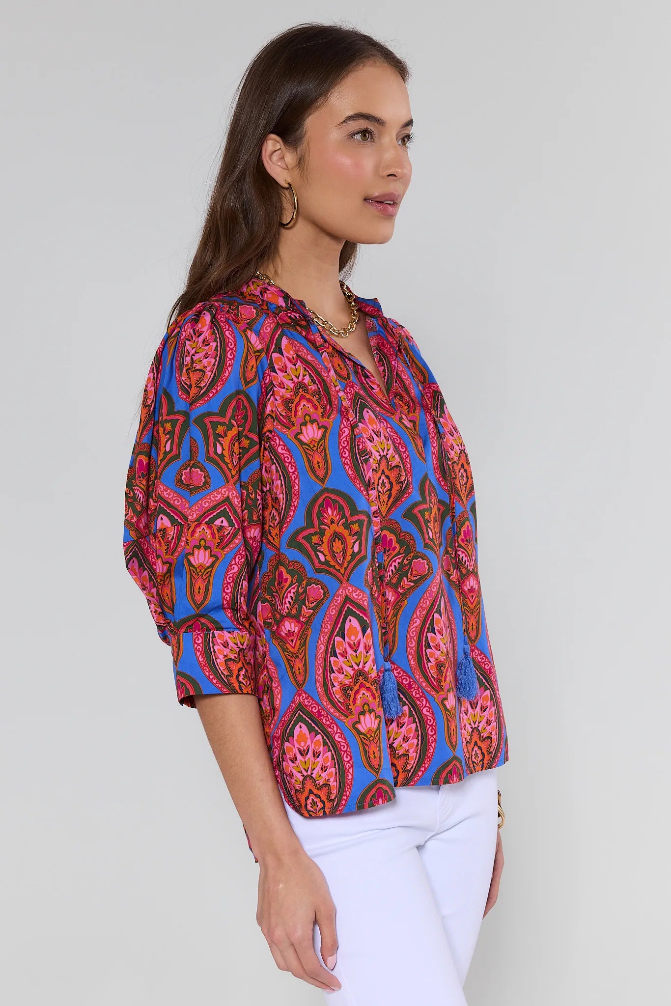 Woman wearing a colorful patterned blouse against a plain background