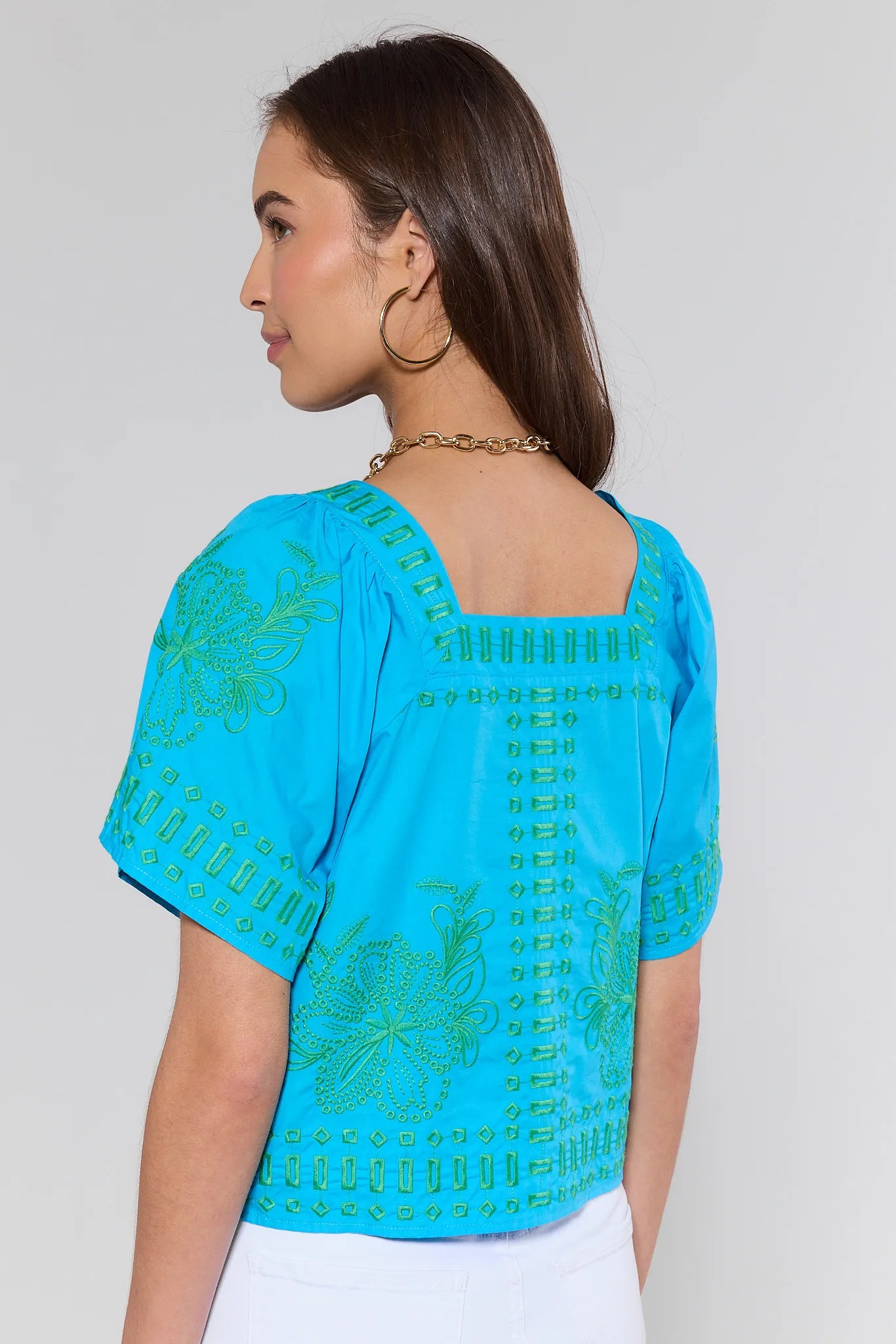 Woman wearing a blue top with patterns on a plain background