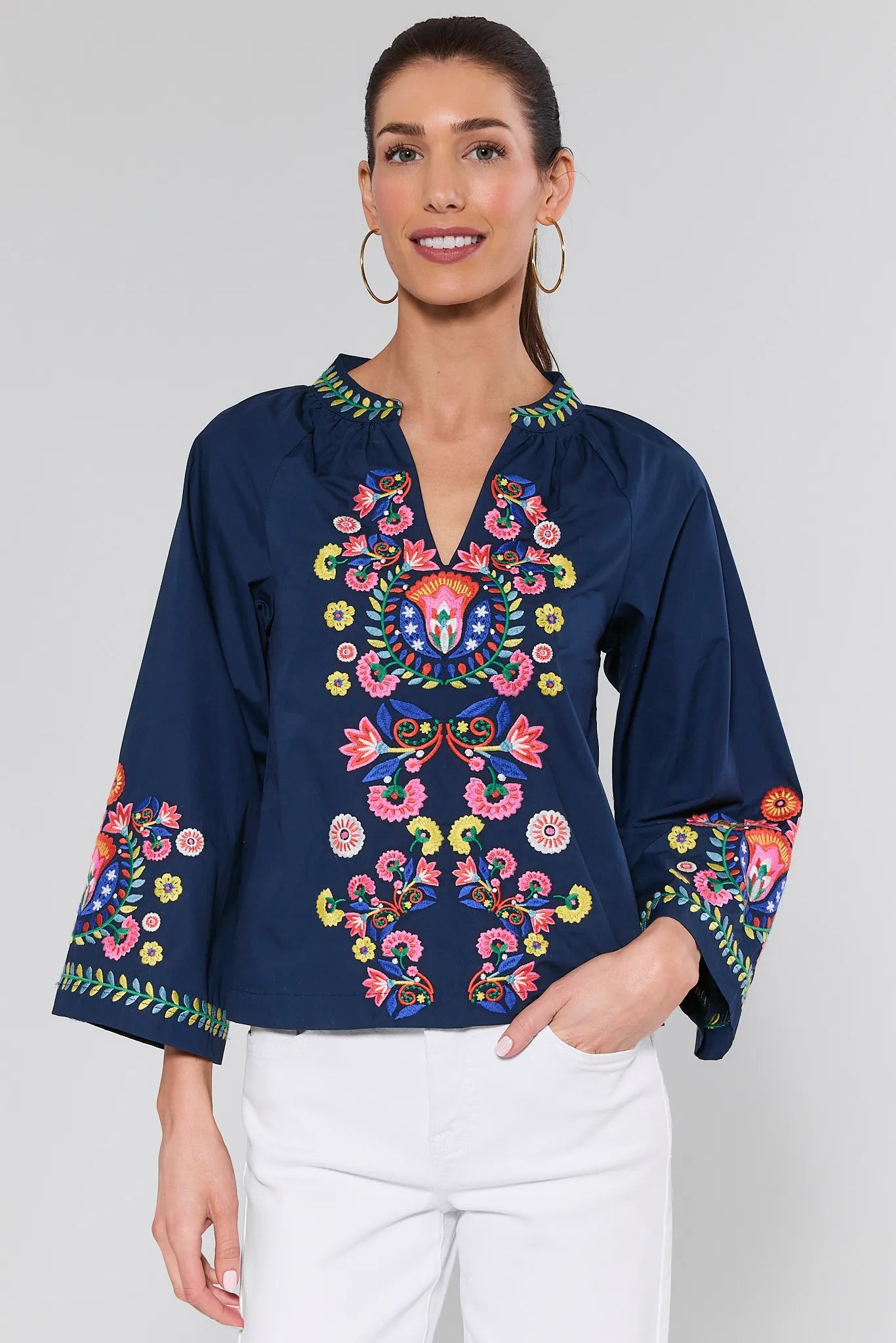 Woman wearing a navy blue blouse with colorful embroidery on a white background