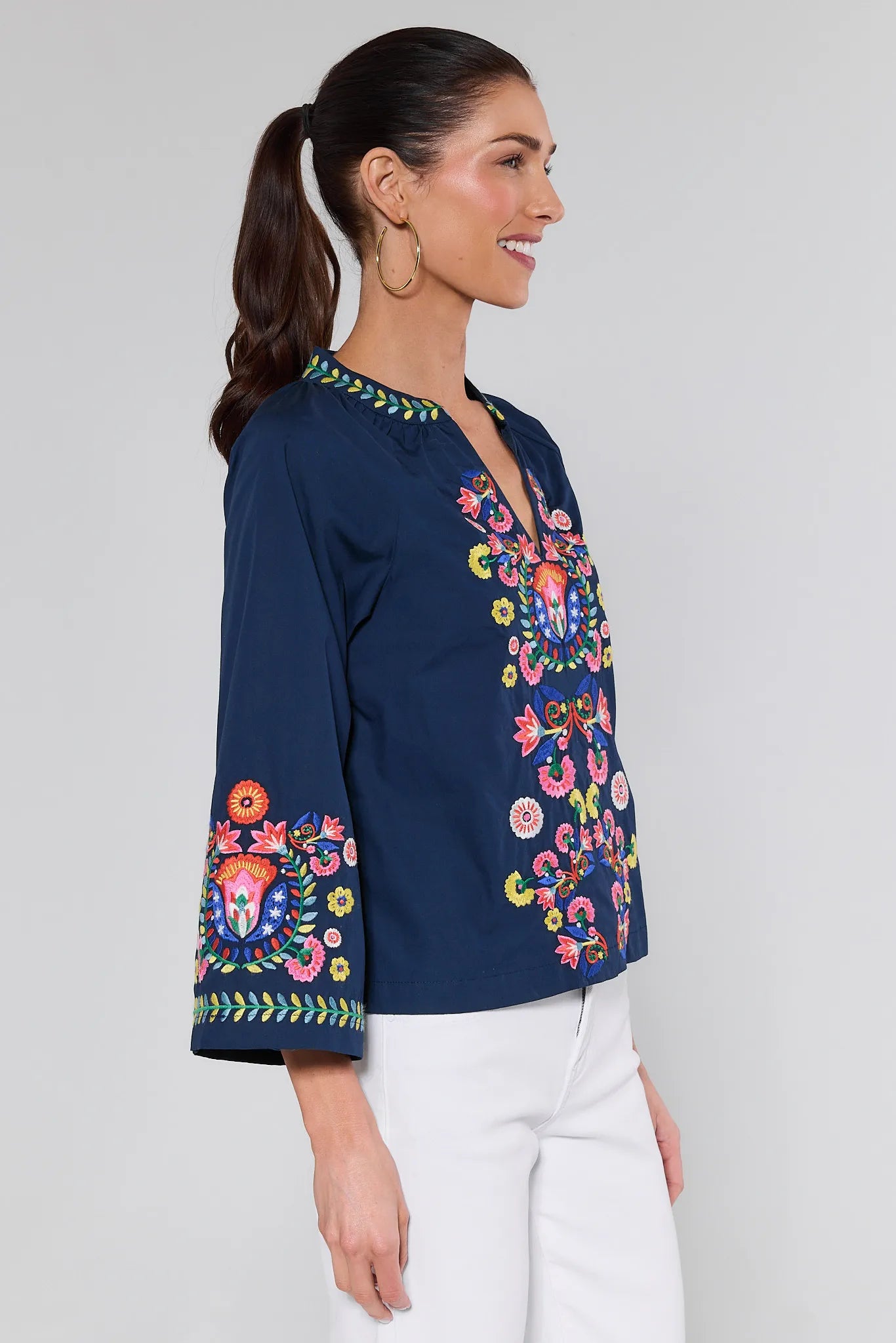 Woman wearing a navy blue blouse with colorful floral embroidery on a white background