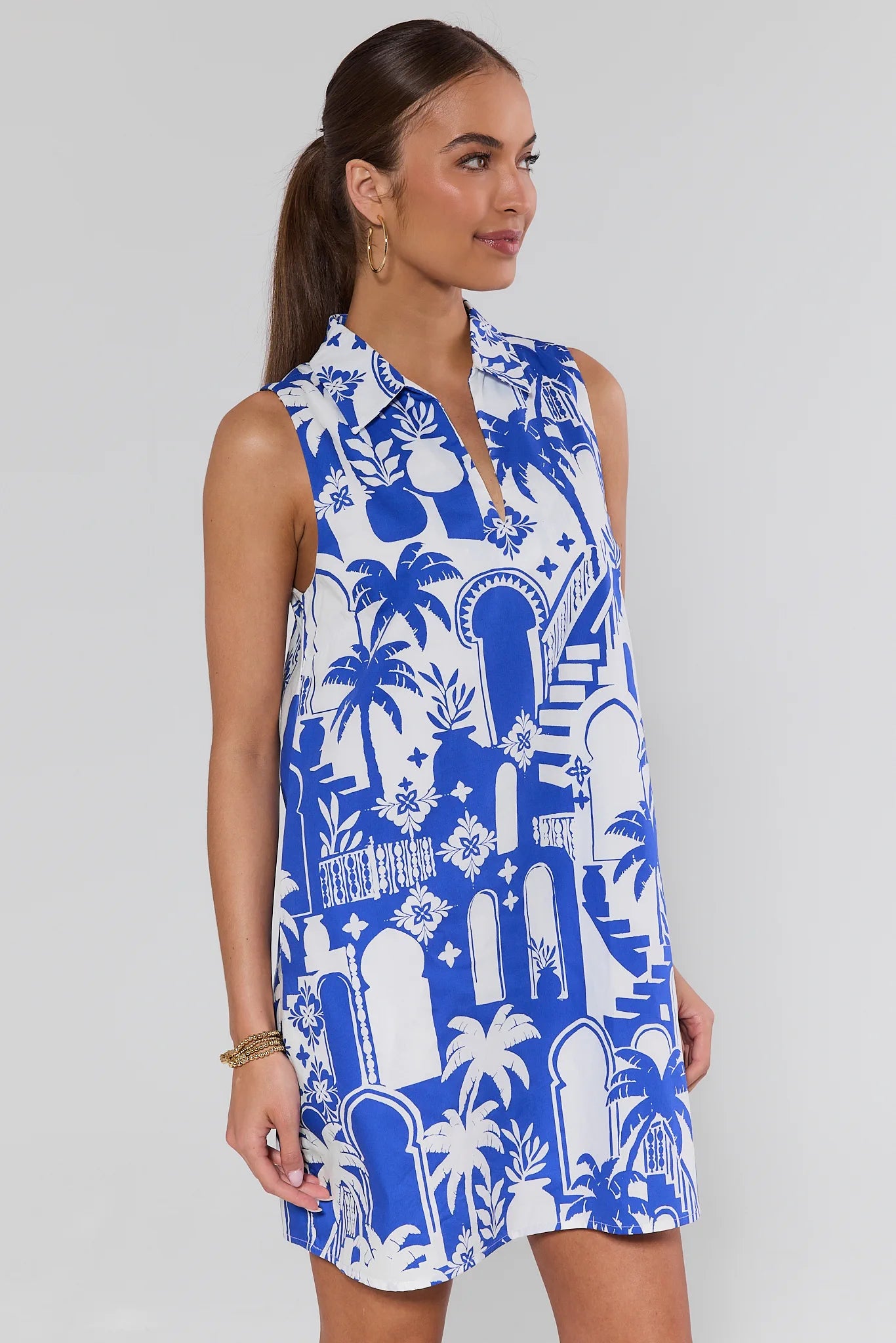 Woman wearing a blue and white patterned sleeveless dress on a plain background