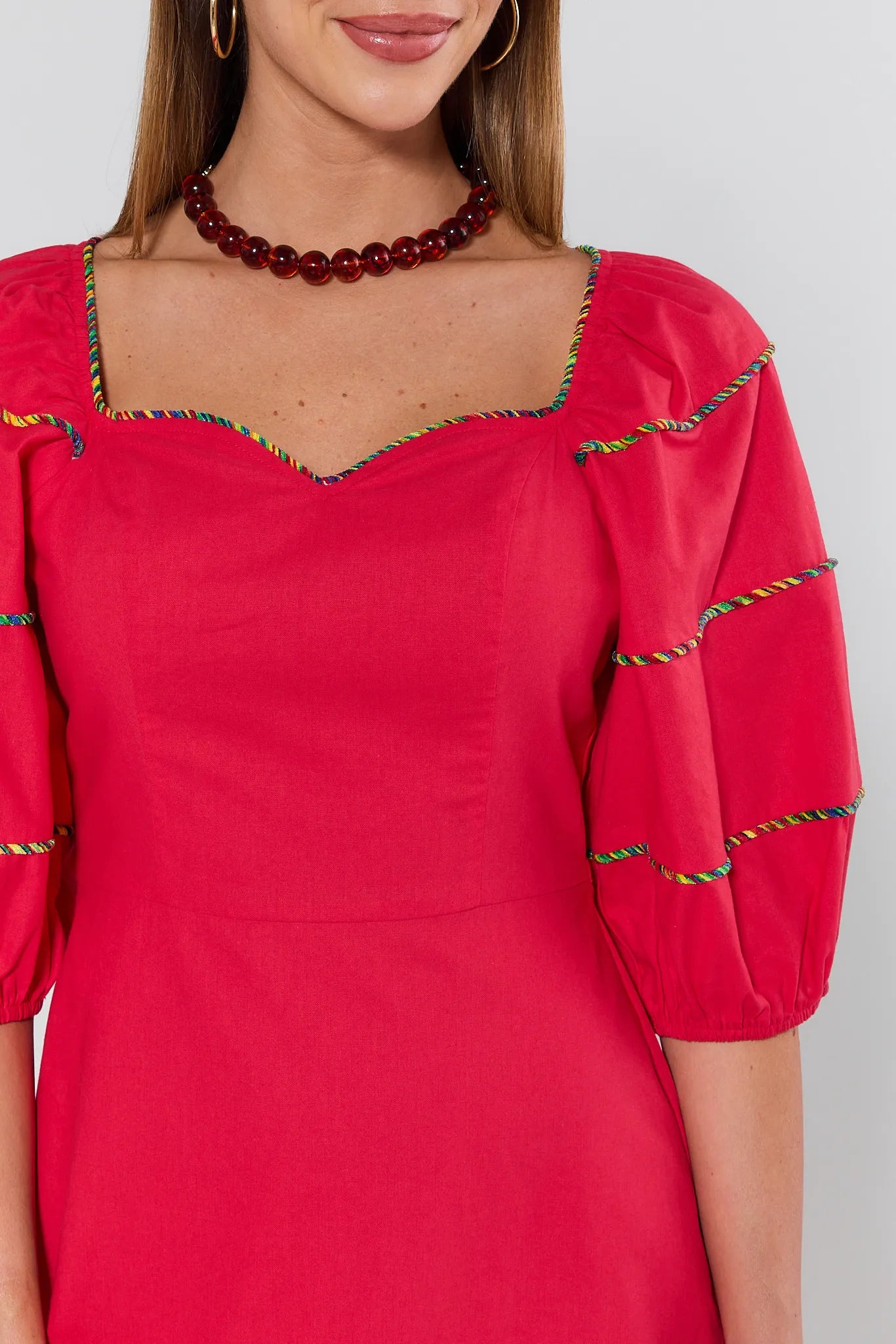 Red dress with decorative neckline and sleeves on a plain background
