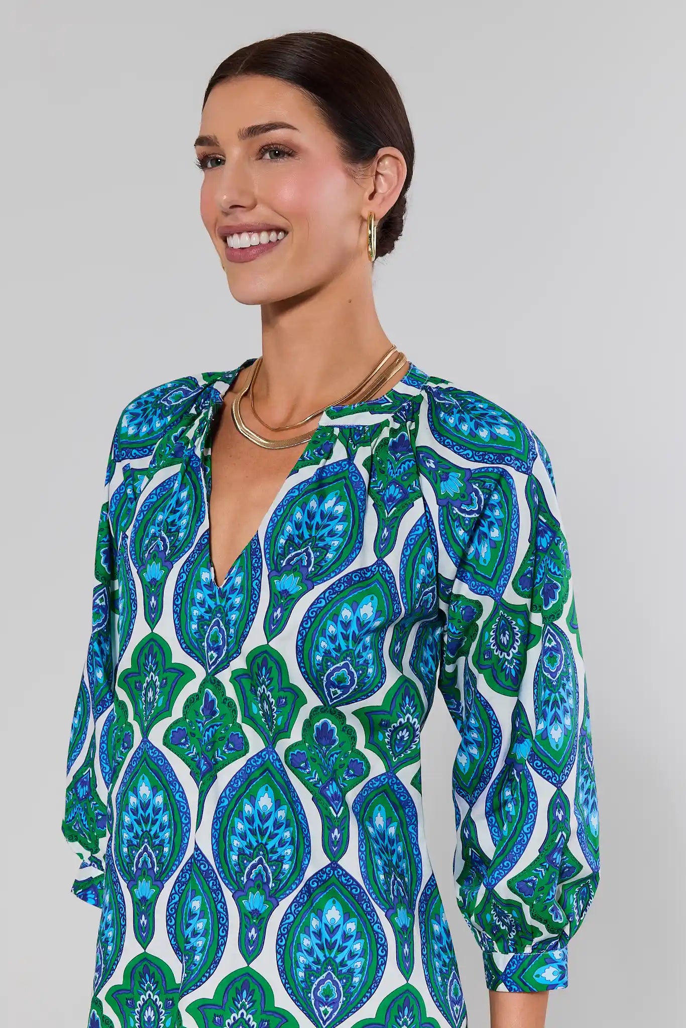 close up Woman wearing a blue and green patterned dress against a gray background