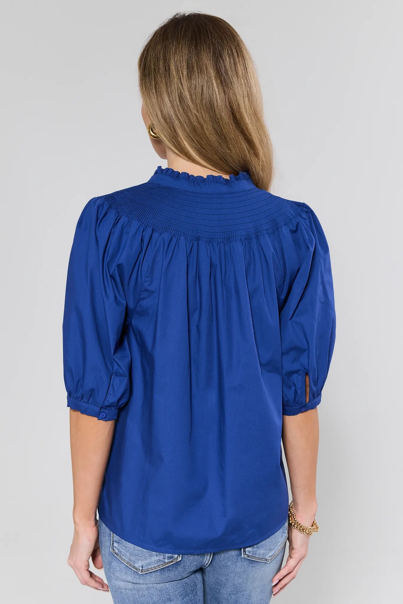 Woman wearing a blue blouse with puffed sleeves against a plain background