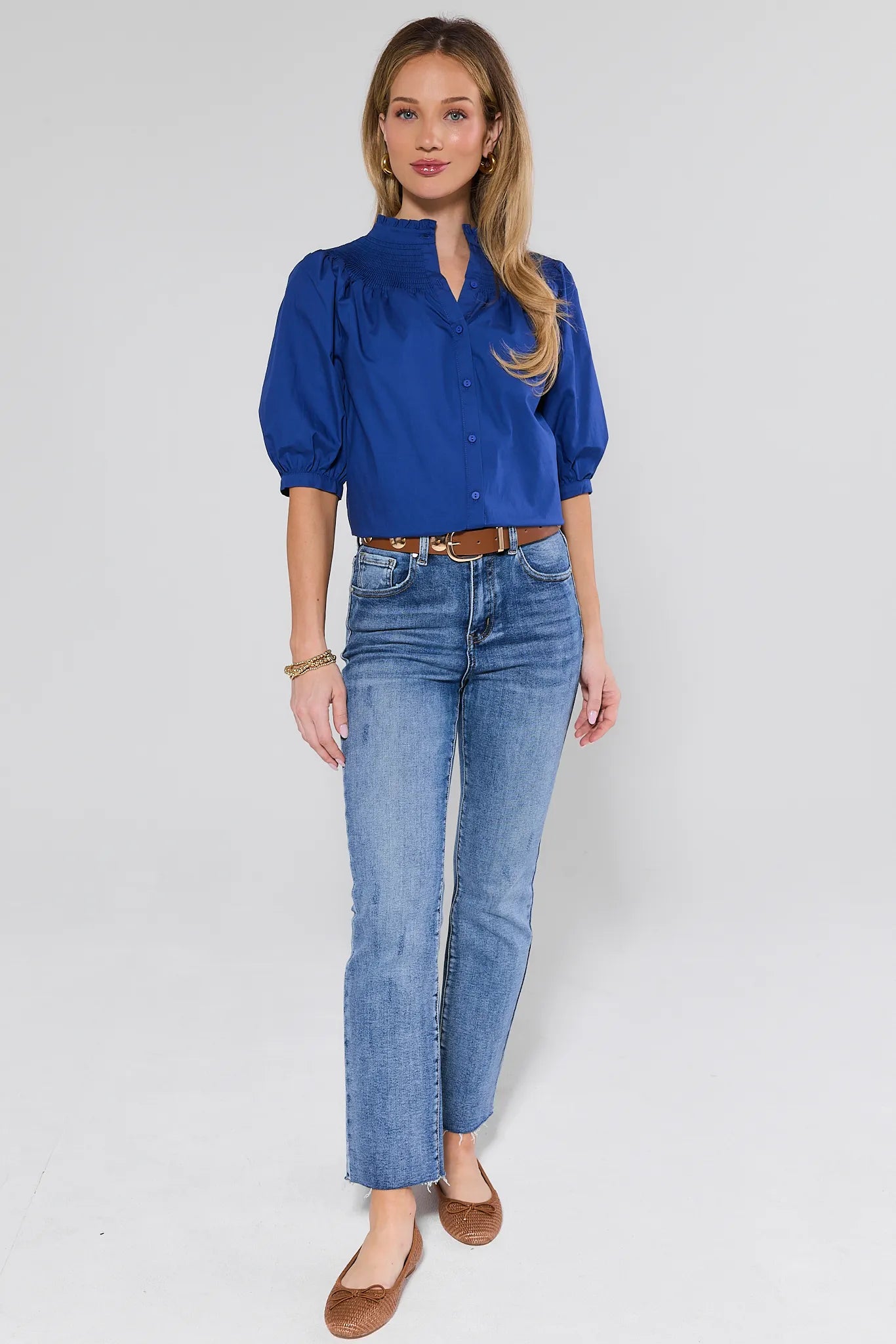 Woman wearing a blue blouse and jeans on a white background