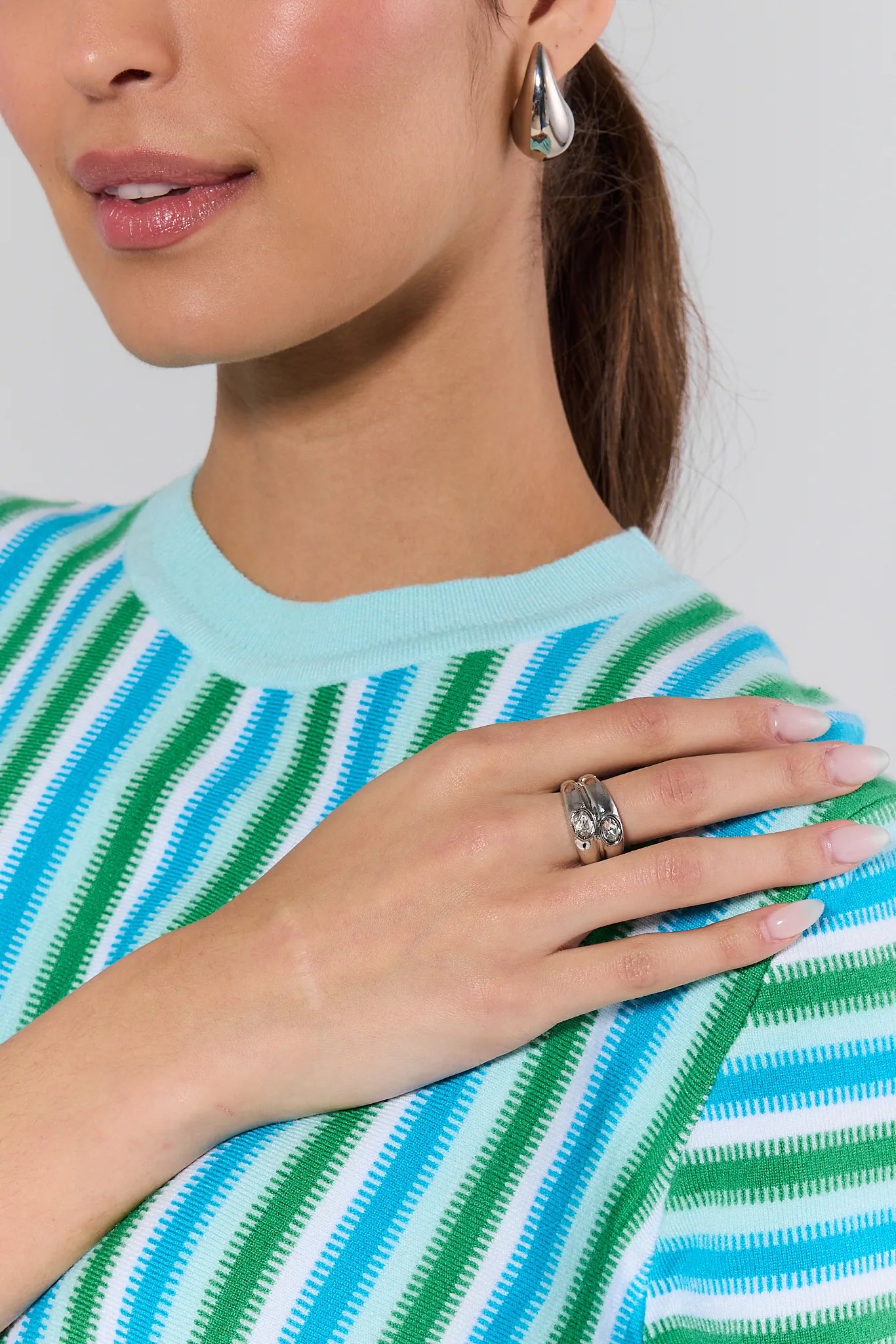 Close-up of a person wearing a blue and green striped shirt with a ring on their finger.