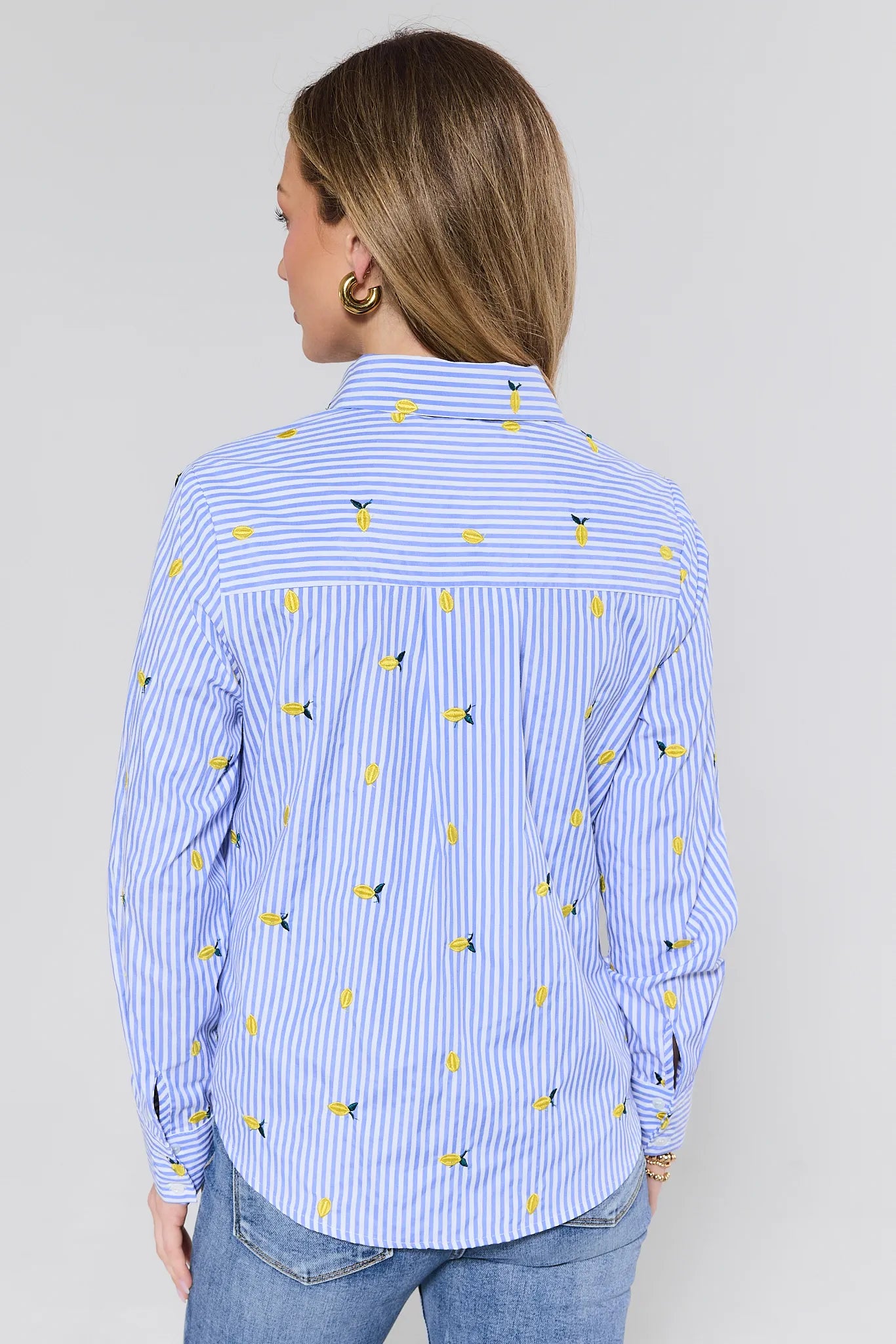 Woman wearing a blue striped shirt with yellow patterns on a plain background