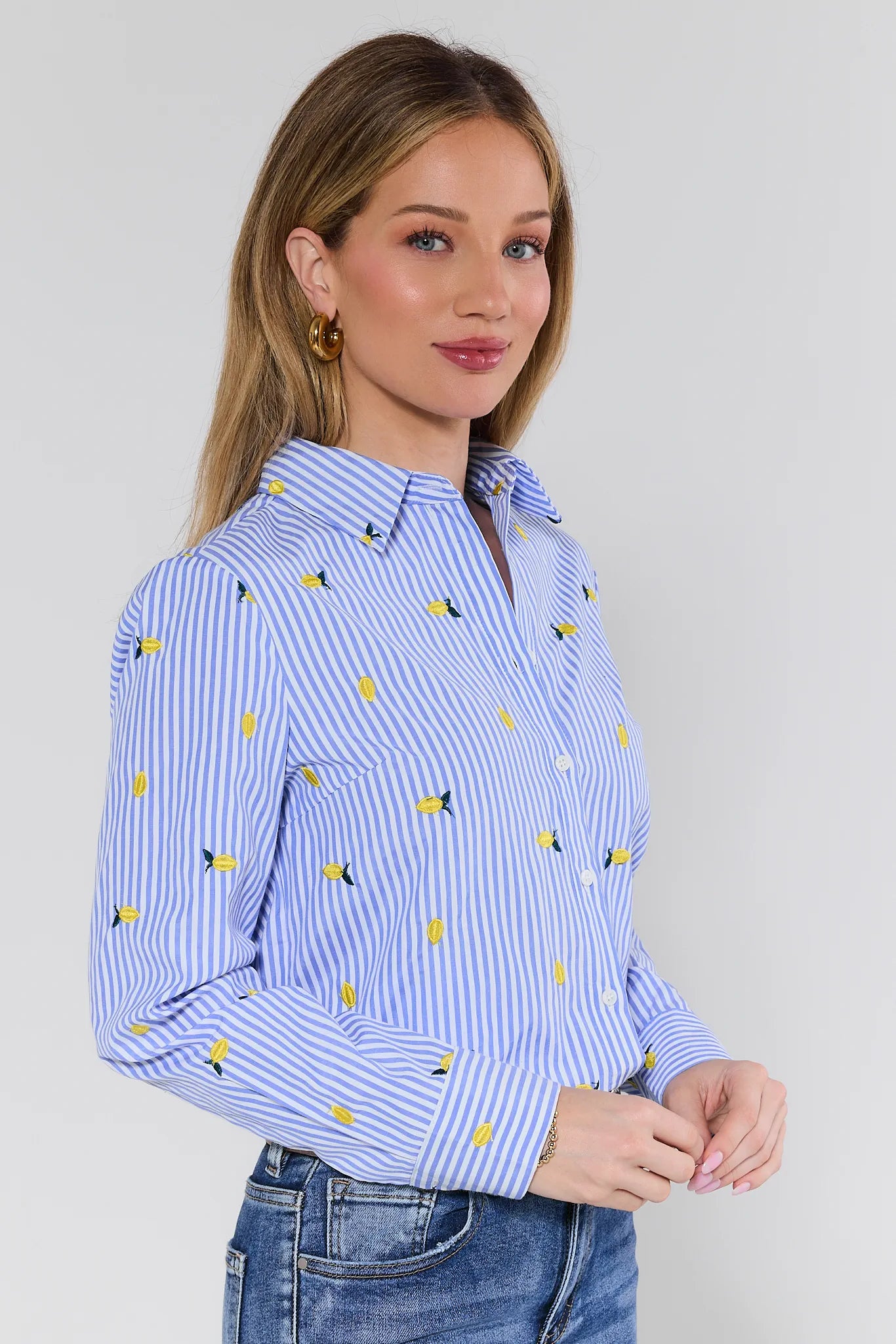 Woman wearing a blue and white striped shirt with yellow patterns on a plain background