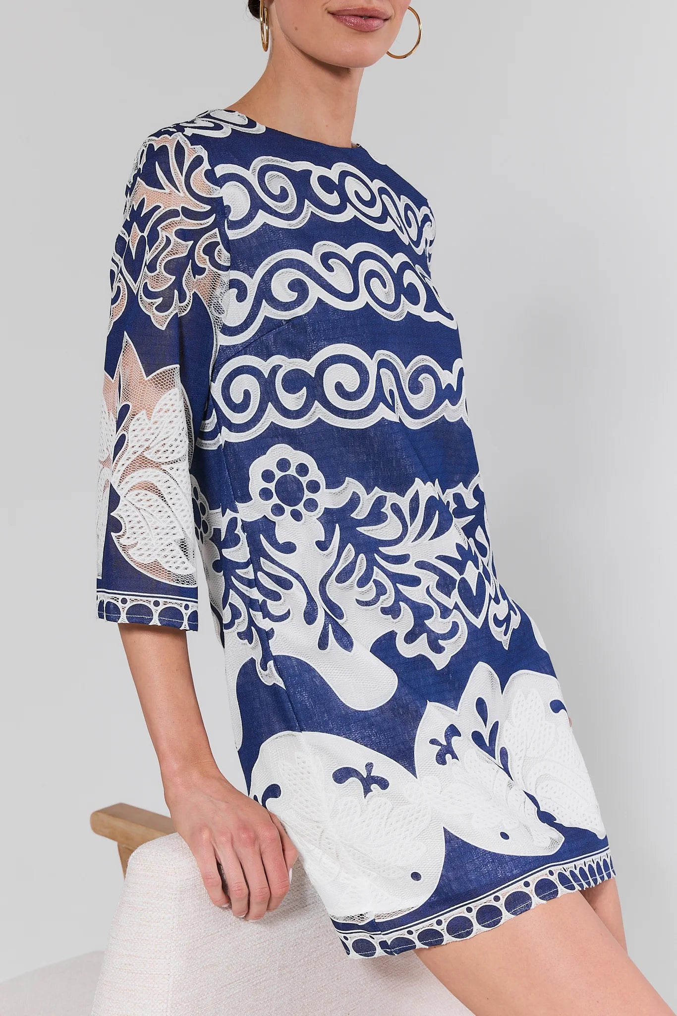 Woman wearing a blue and white patterned dress on a light gray background