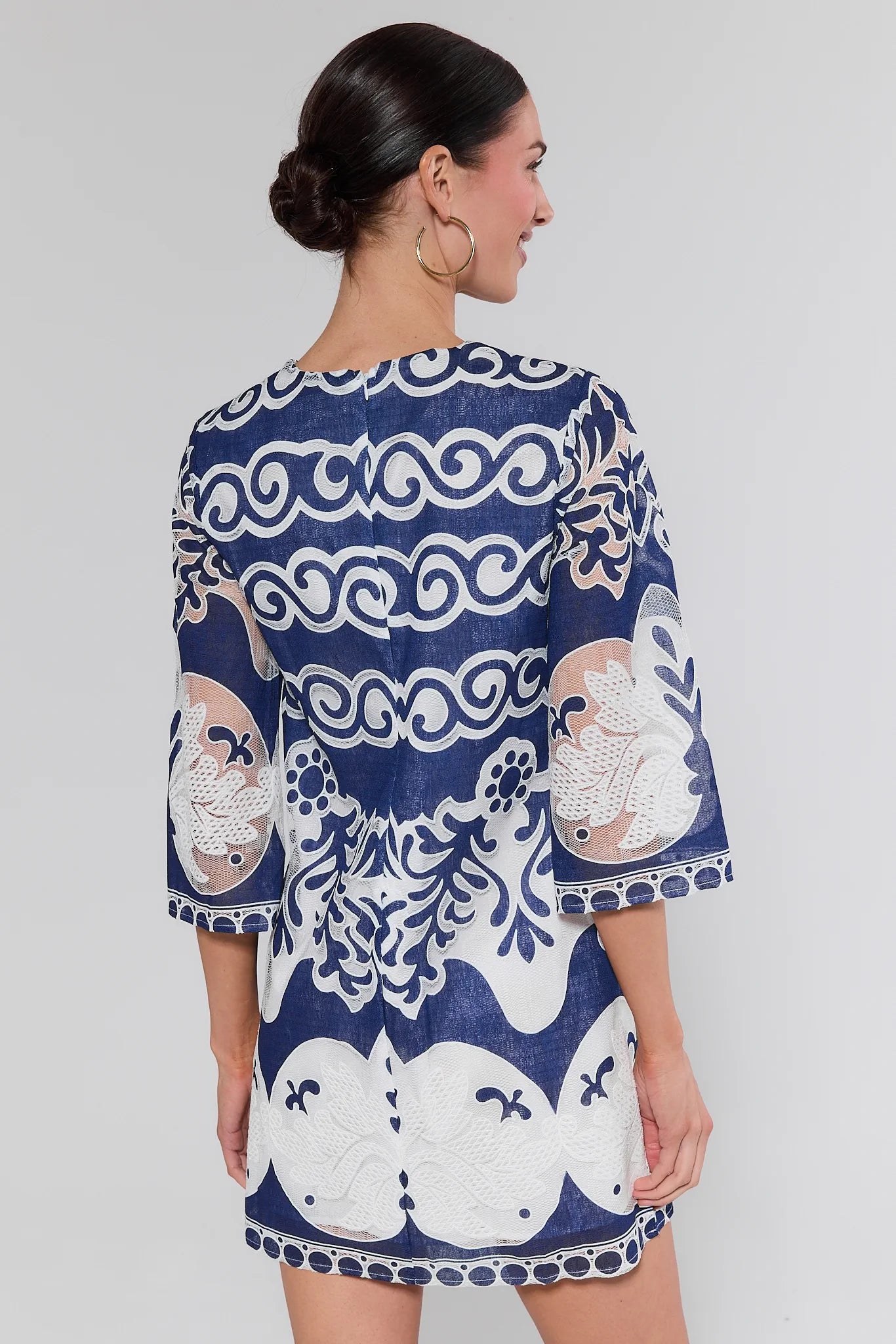 Woman wearing a blue and white patterned dress on a gray background