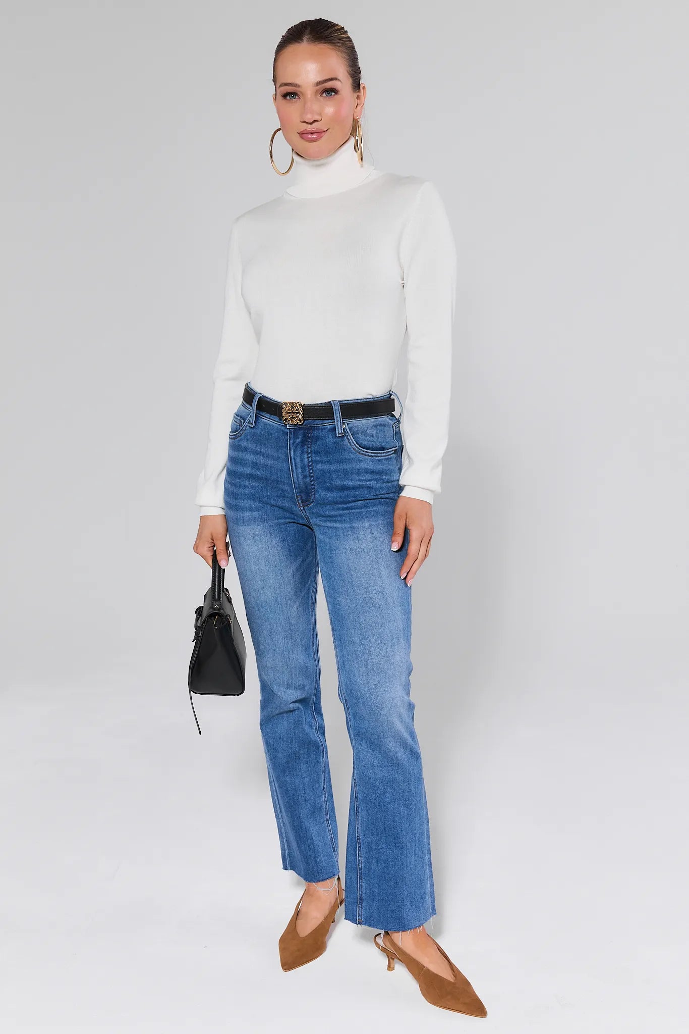 Woman wearing a Andrea Ivory Turtleneck Top sweater with gold hoop earrings on a plain background