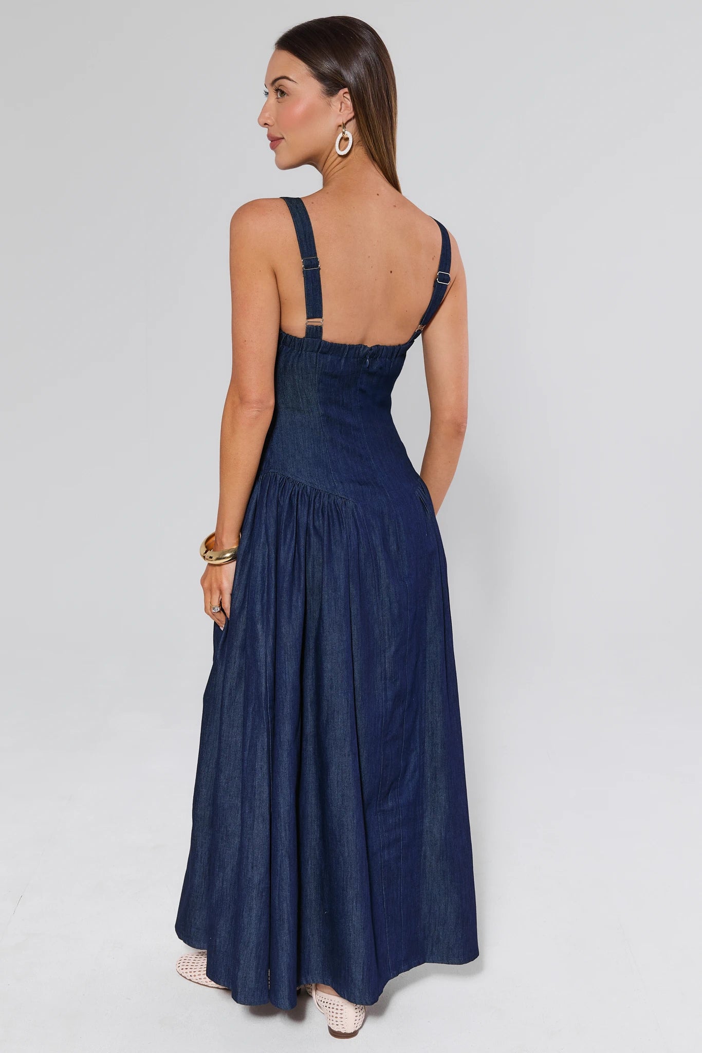 Woman wearing a navy blue dress with thin straps on a white background