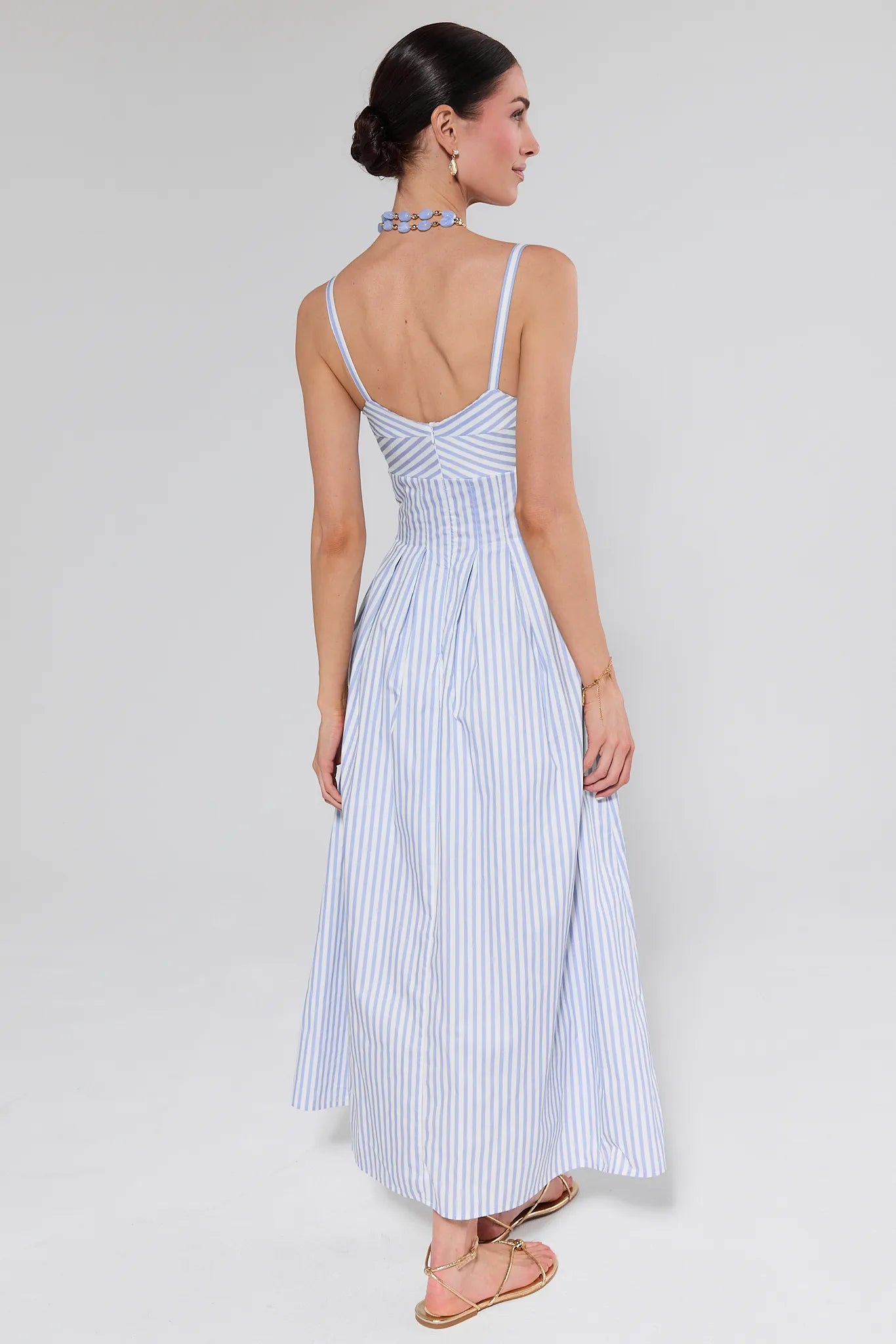 Woman wearing a blue and white striped dress against a white background