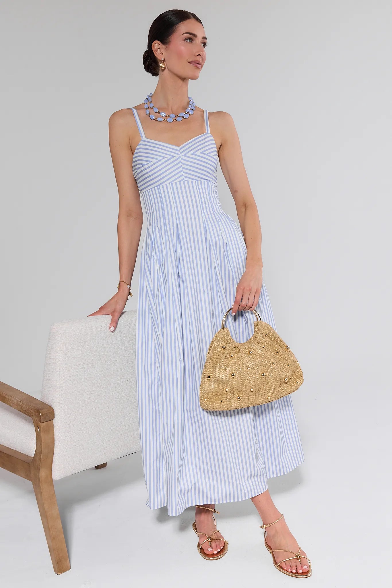 Woman wearing a blue and white striped dress against a white background