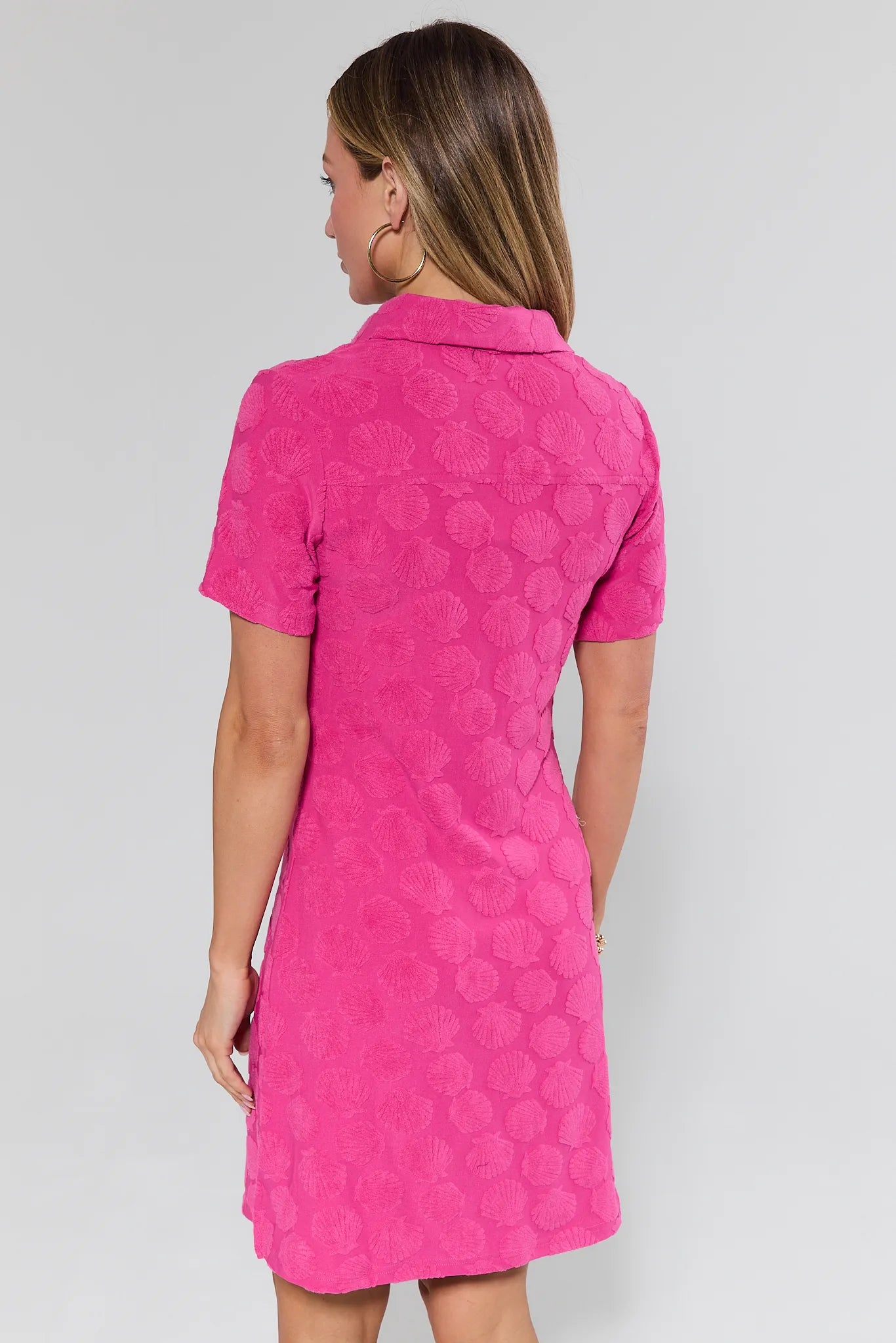 Woman wearing a pink dress with a pattern on a plain background