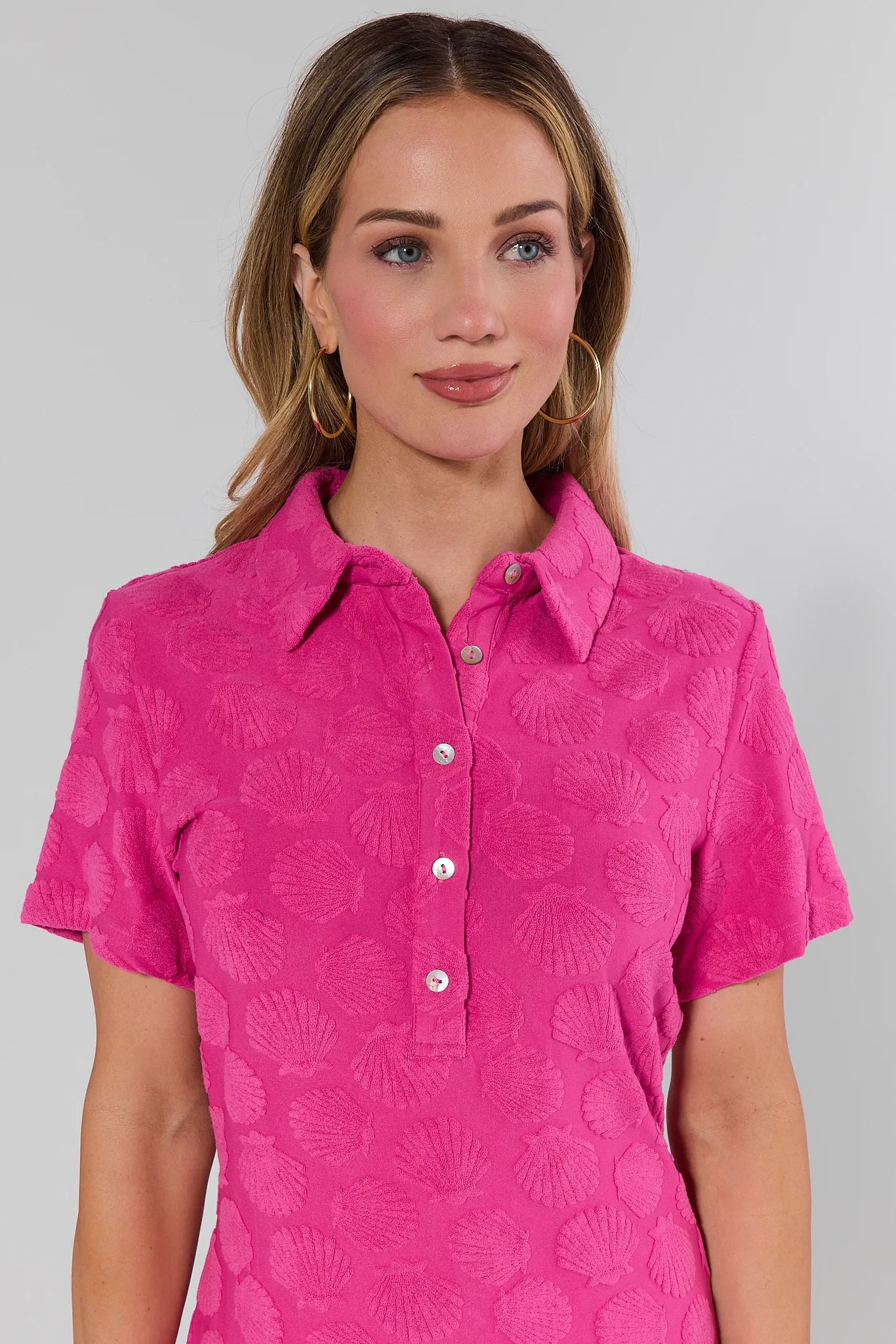 Woman wearing a pink patterned shirt against a gray background