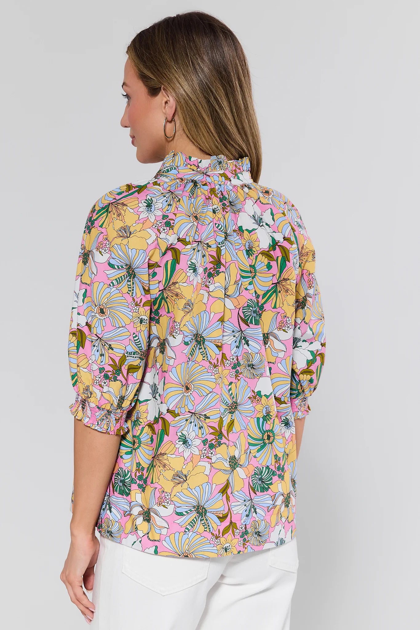 Woman wearing a colorful floral blouse against a white background