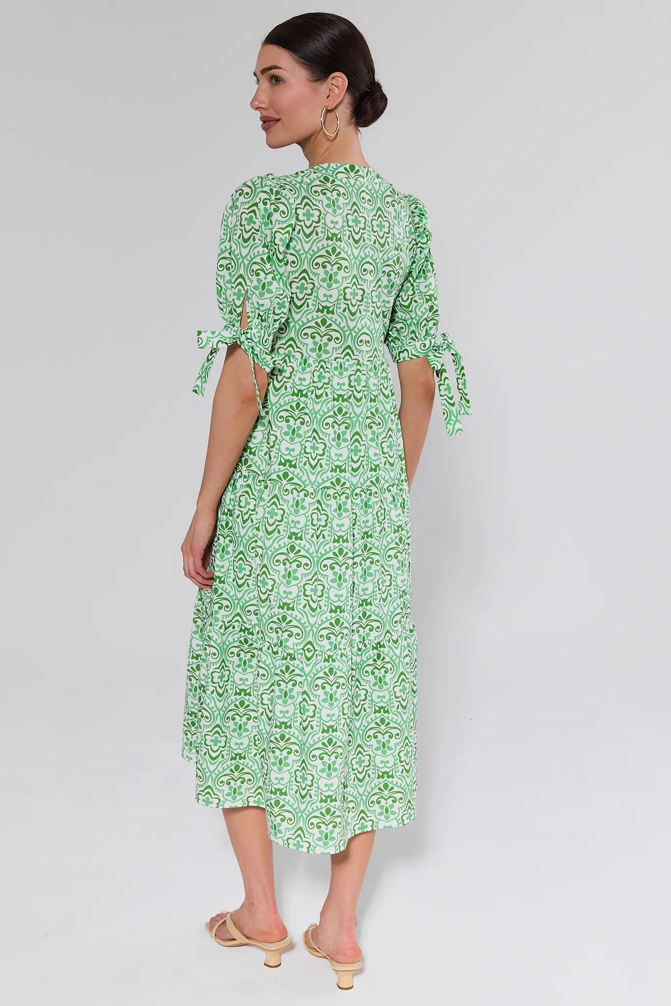 Woman wearing a green patterned dress on a white background