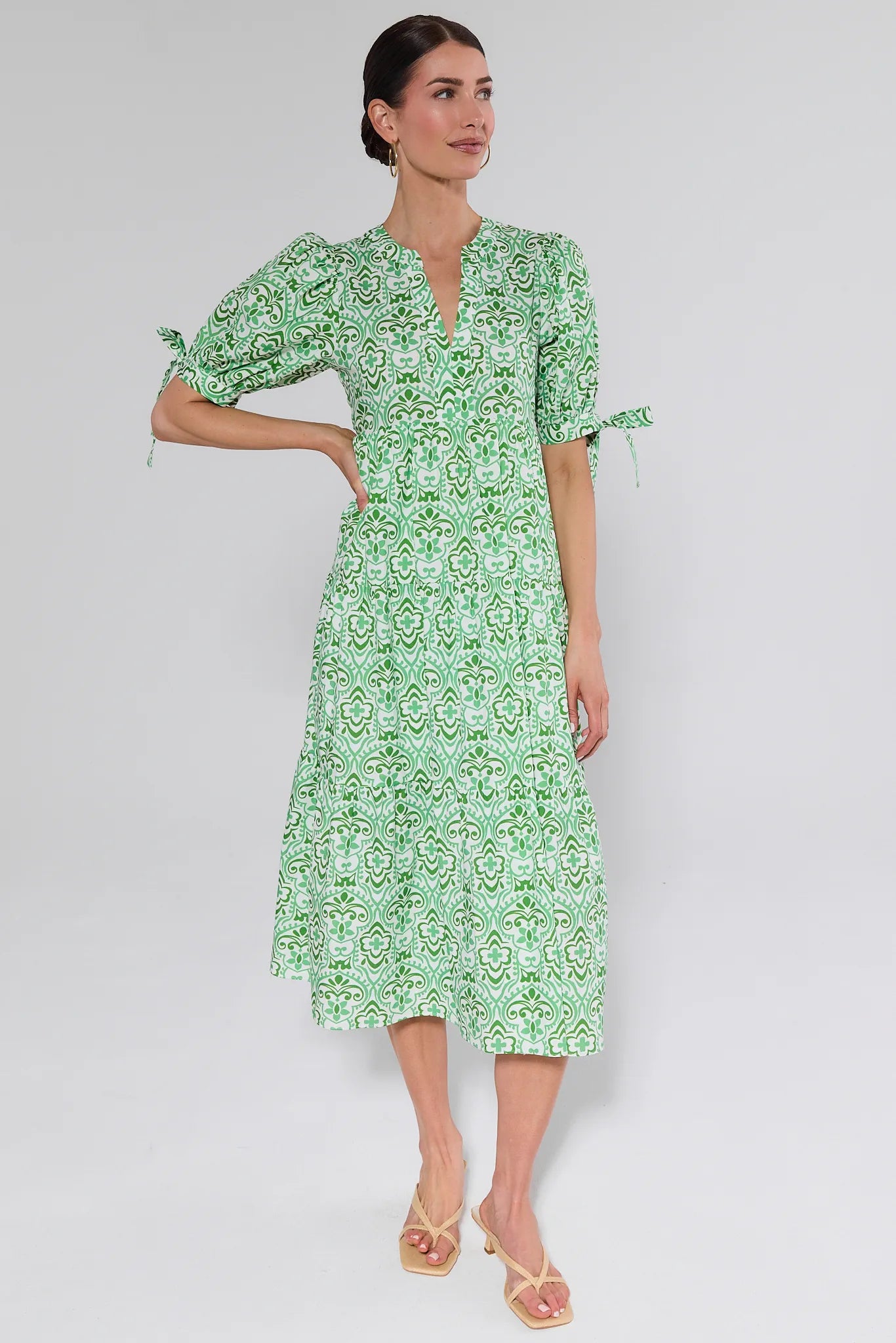 Woman wearing a green patterned dress on a white background
