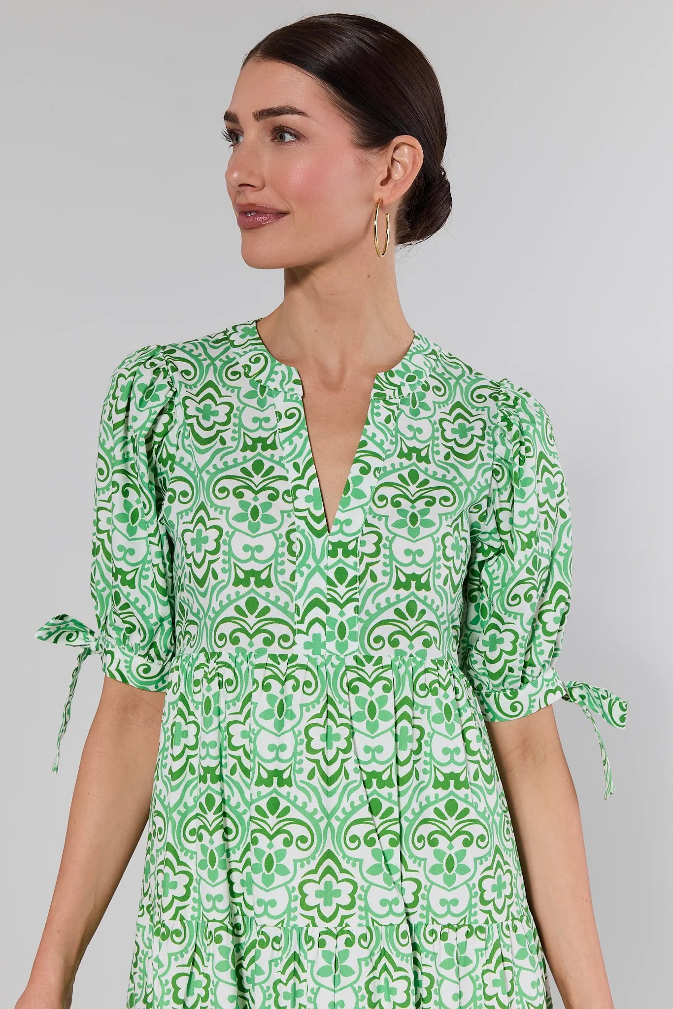 Woman wearing a green patterned dress against a gray background