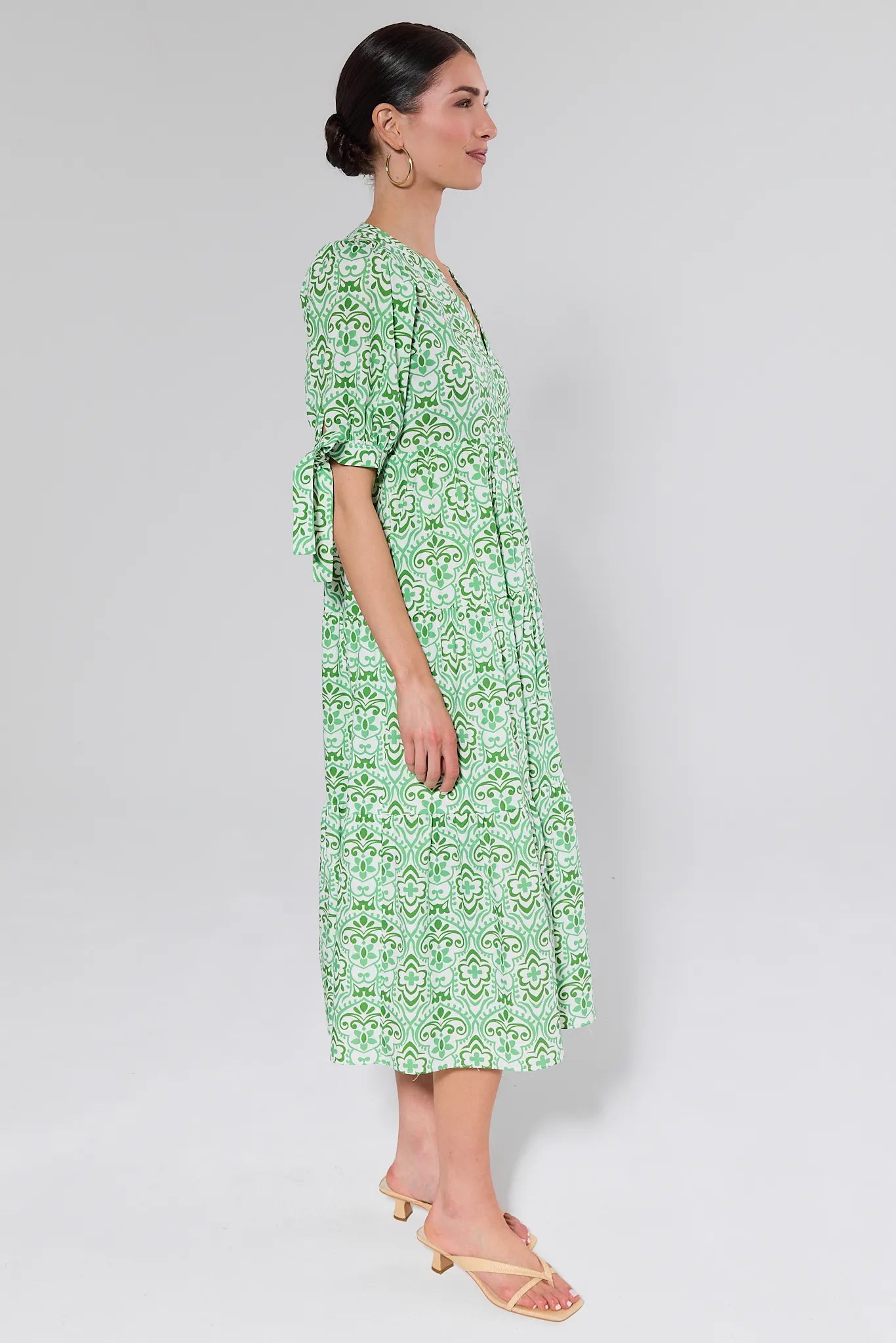 Woman wearing a green patterned Harriet dress on a white background