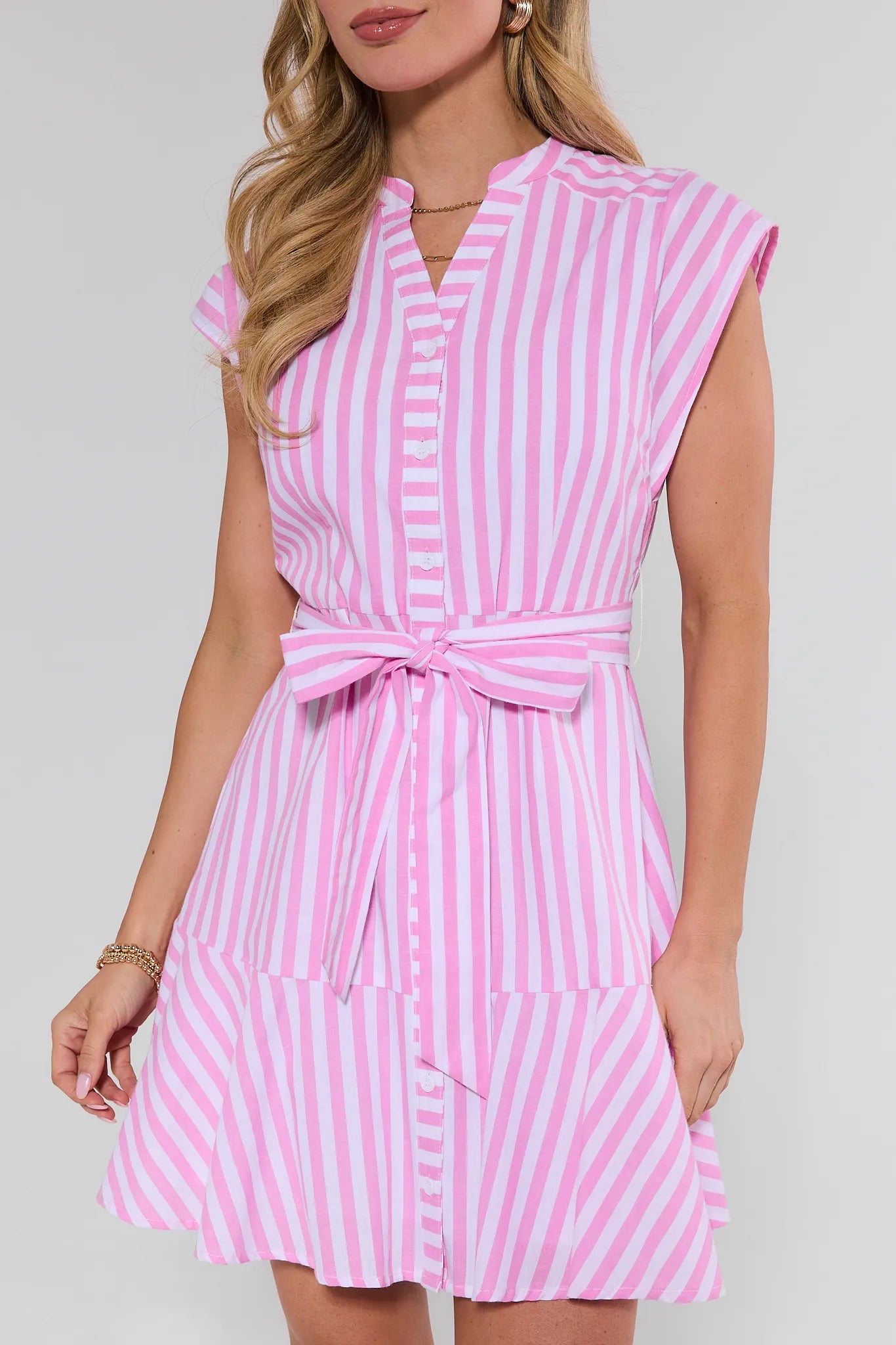 Woman wearing a pink and white striped dress against a plain background