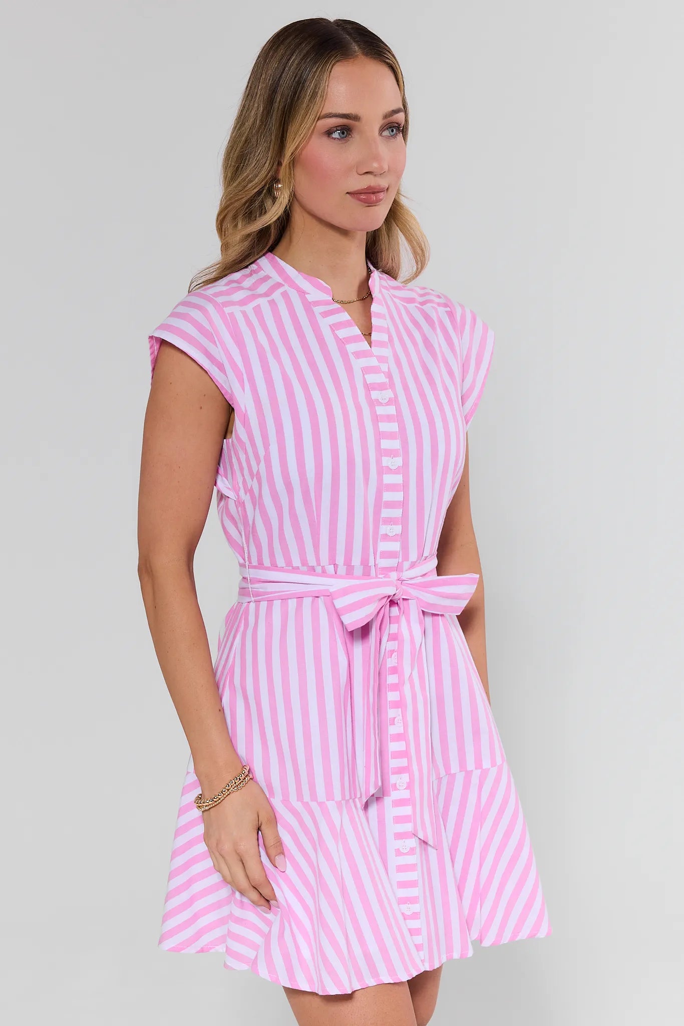 Woman wearing a pink and white striped dress on a gray background
