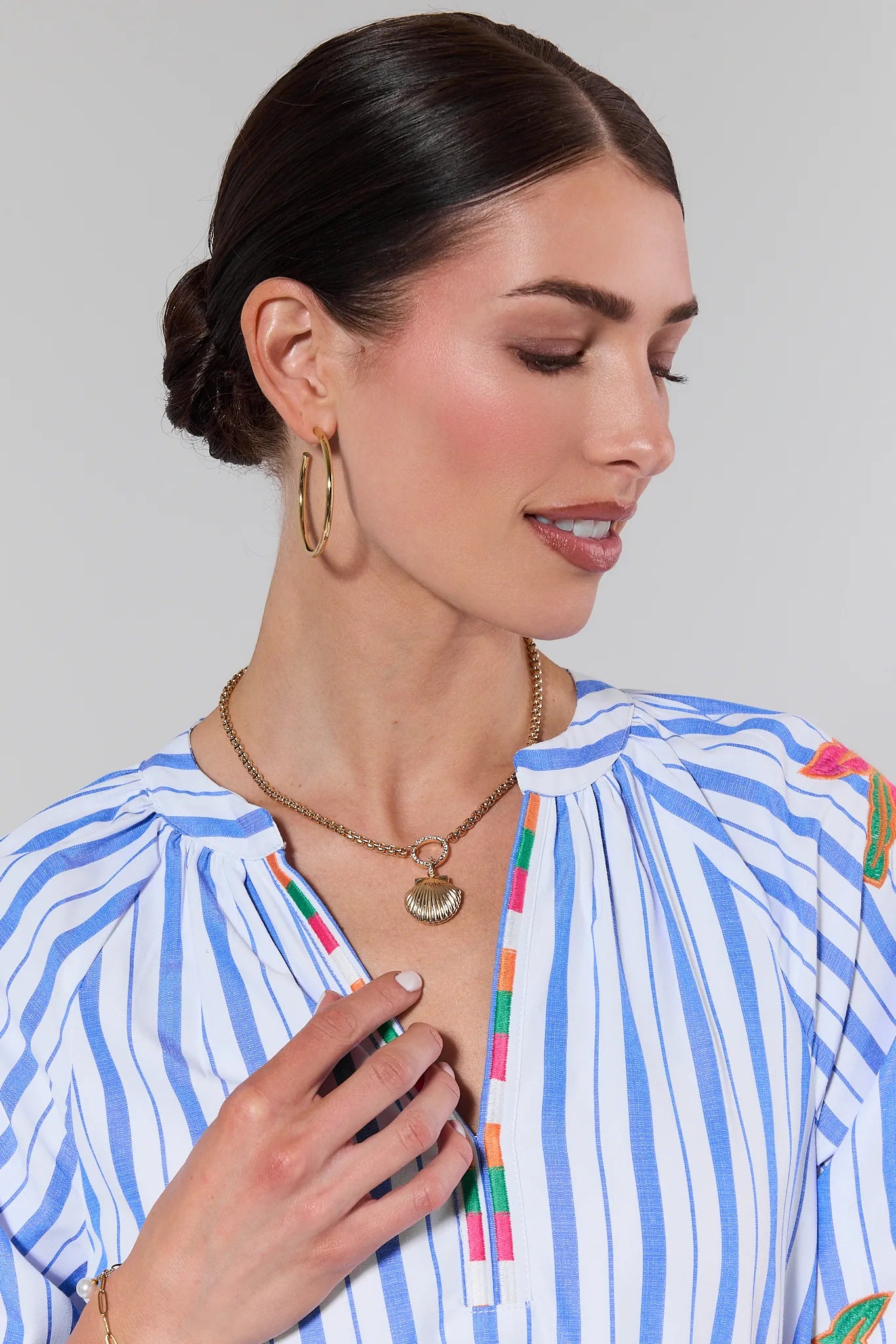 Woman wearing a blue and white striped shirt with colorful accents on a plain background