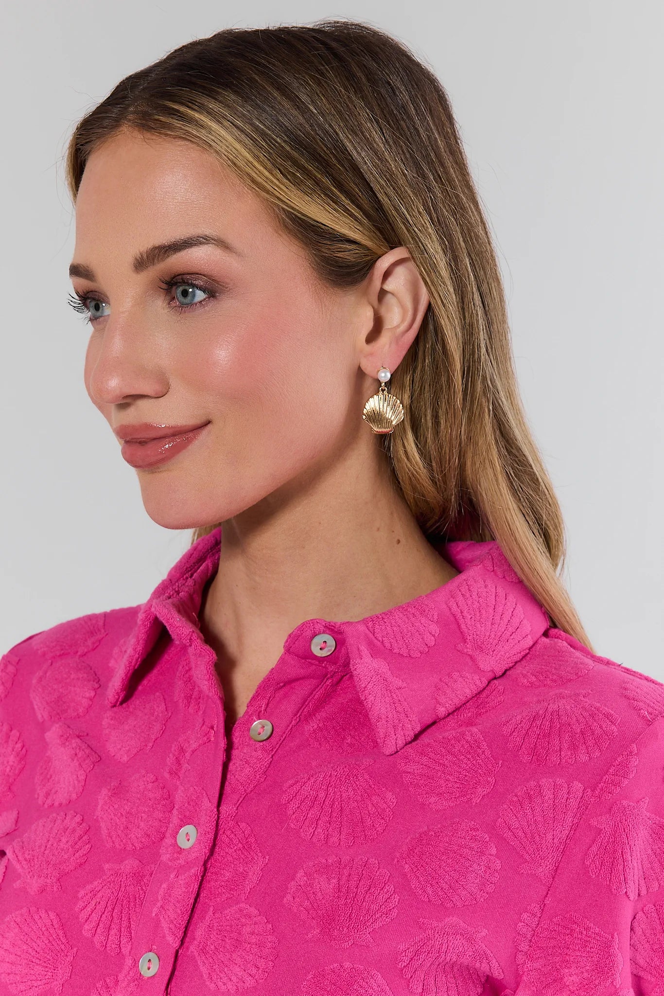 Woman wearing a pink patterned shirt with a plain background