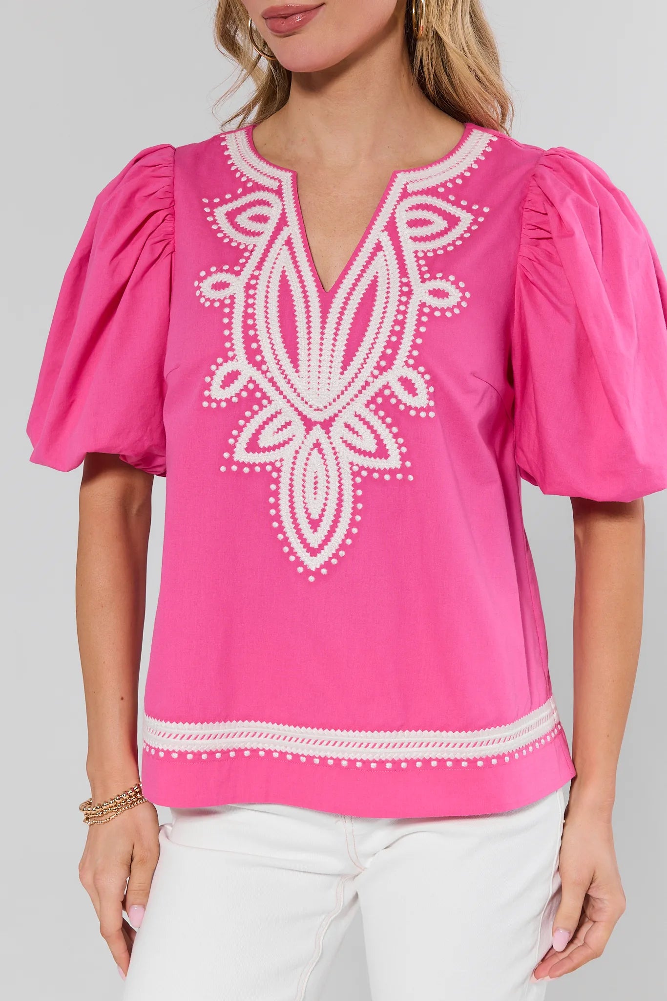 Pink blouse with white embroidery on a plain background