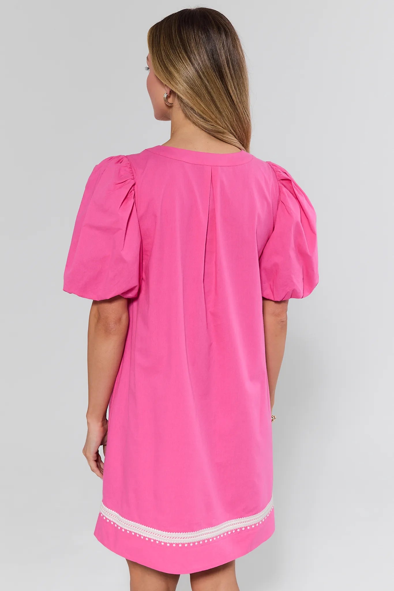 Woman wearing a pink dress with puff sleeves on a white background