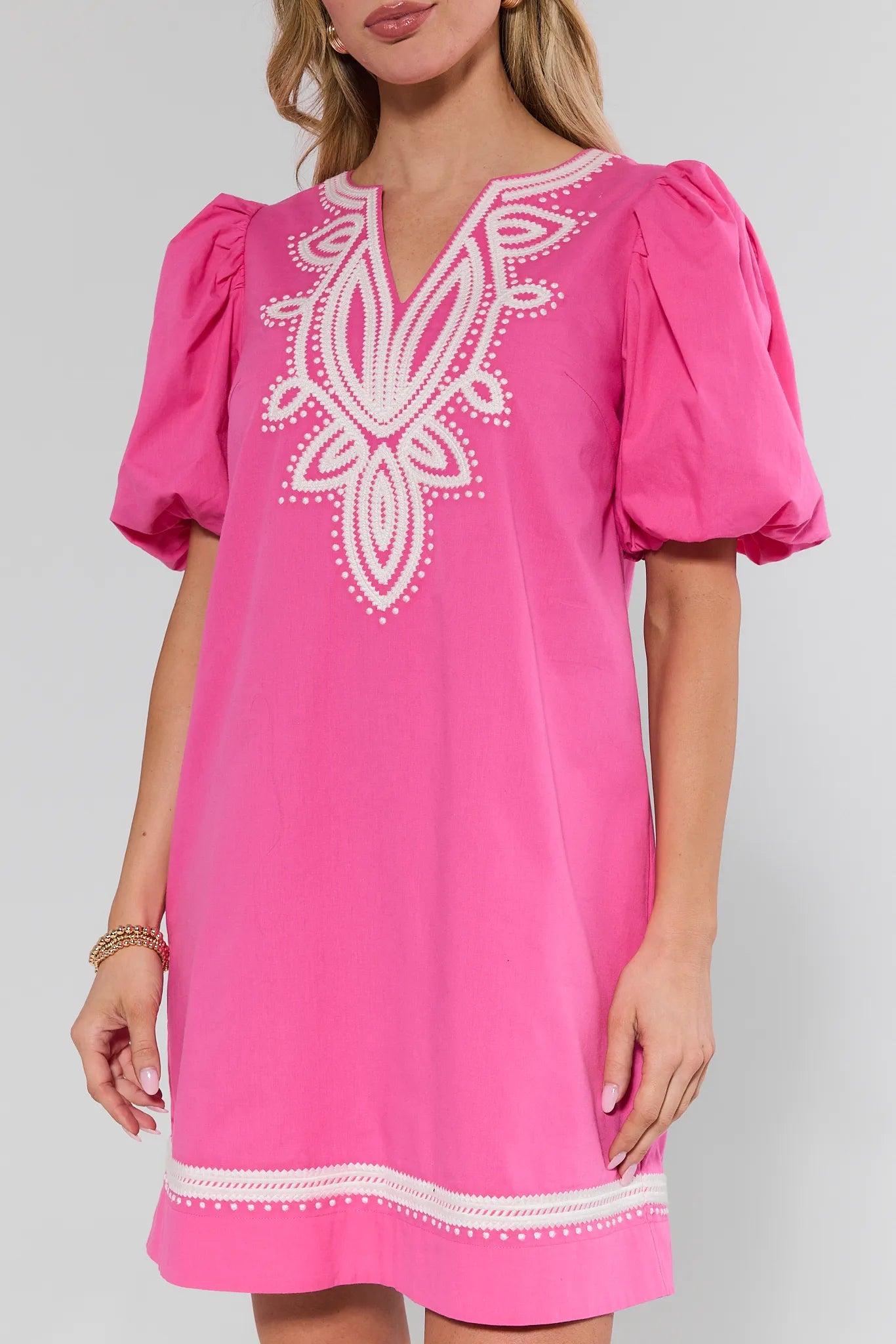 Pink dress with white embroidery on a plain background