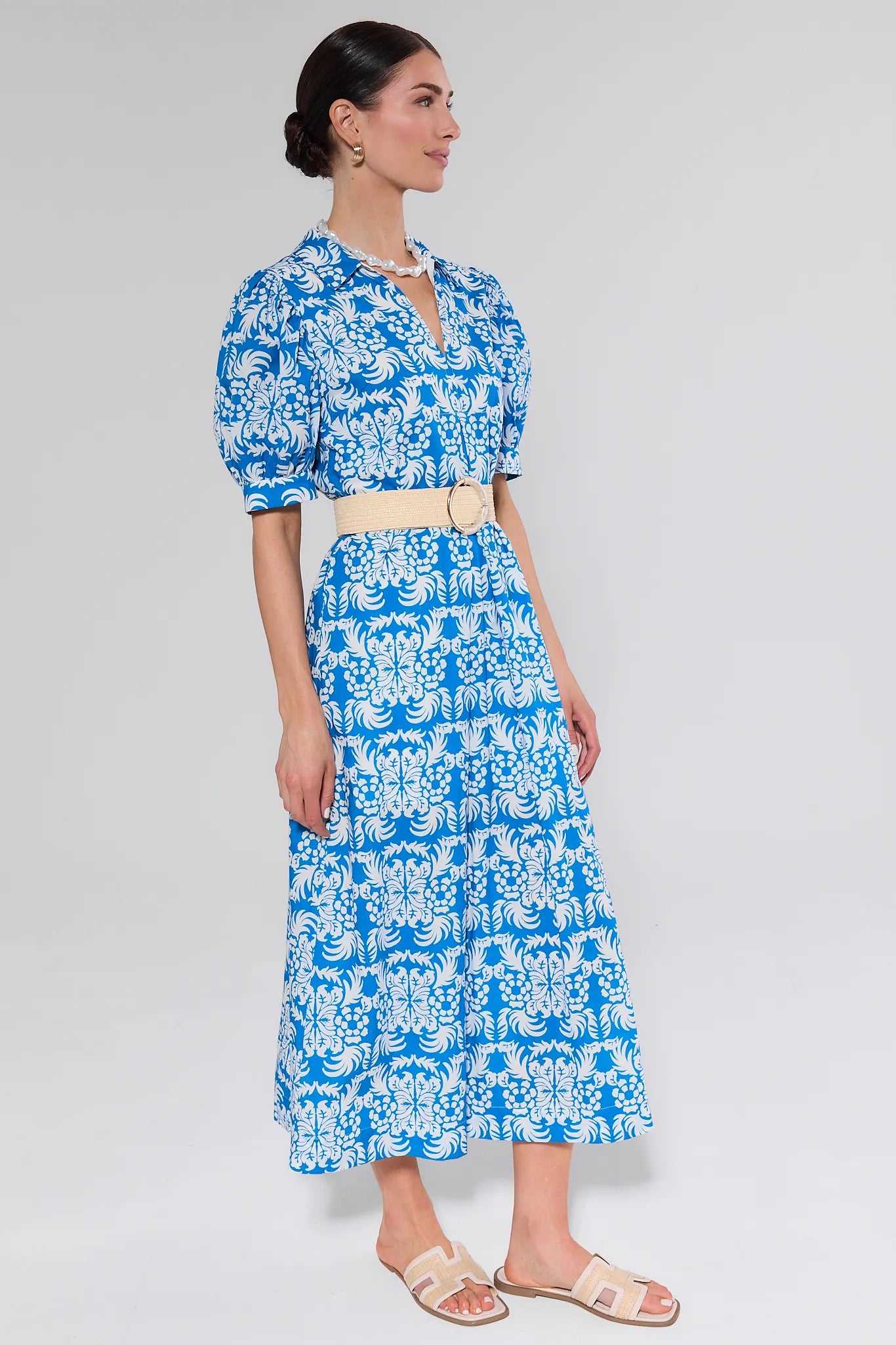 Woman wearing a blue floral dress on a gray background